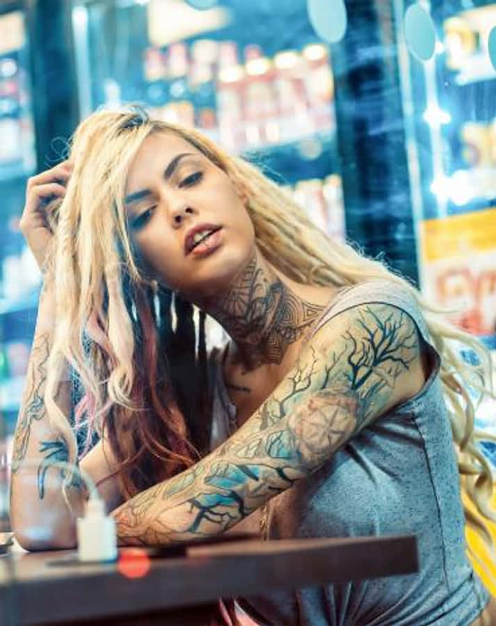 Tattoo 桌布 壁紙 — 一位有刺青的金髮女子靠在光線明亮的便利商店櫃檯上，身後霓虹招牌閃爍。