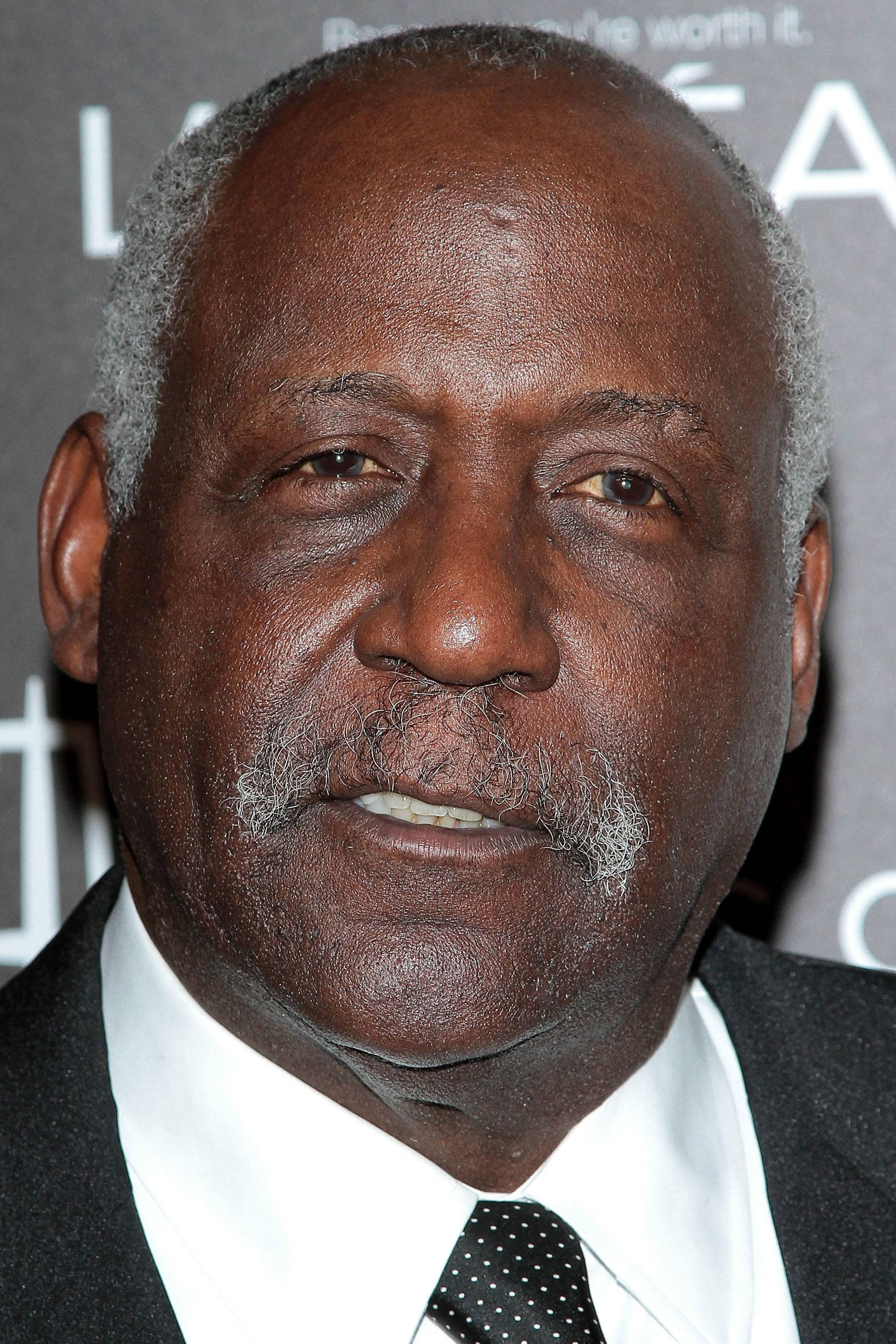 actor 桌布 壁紙 — 一位有尊嚴的年長黑人男性特寫肖像，灰白頭髮和鬍子，穿著西裝和波點領帶出席活動。