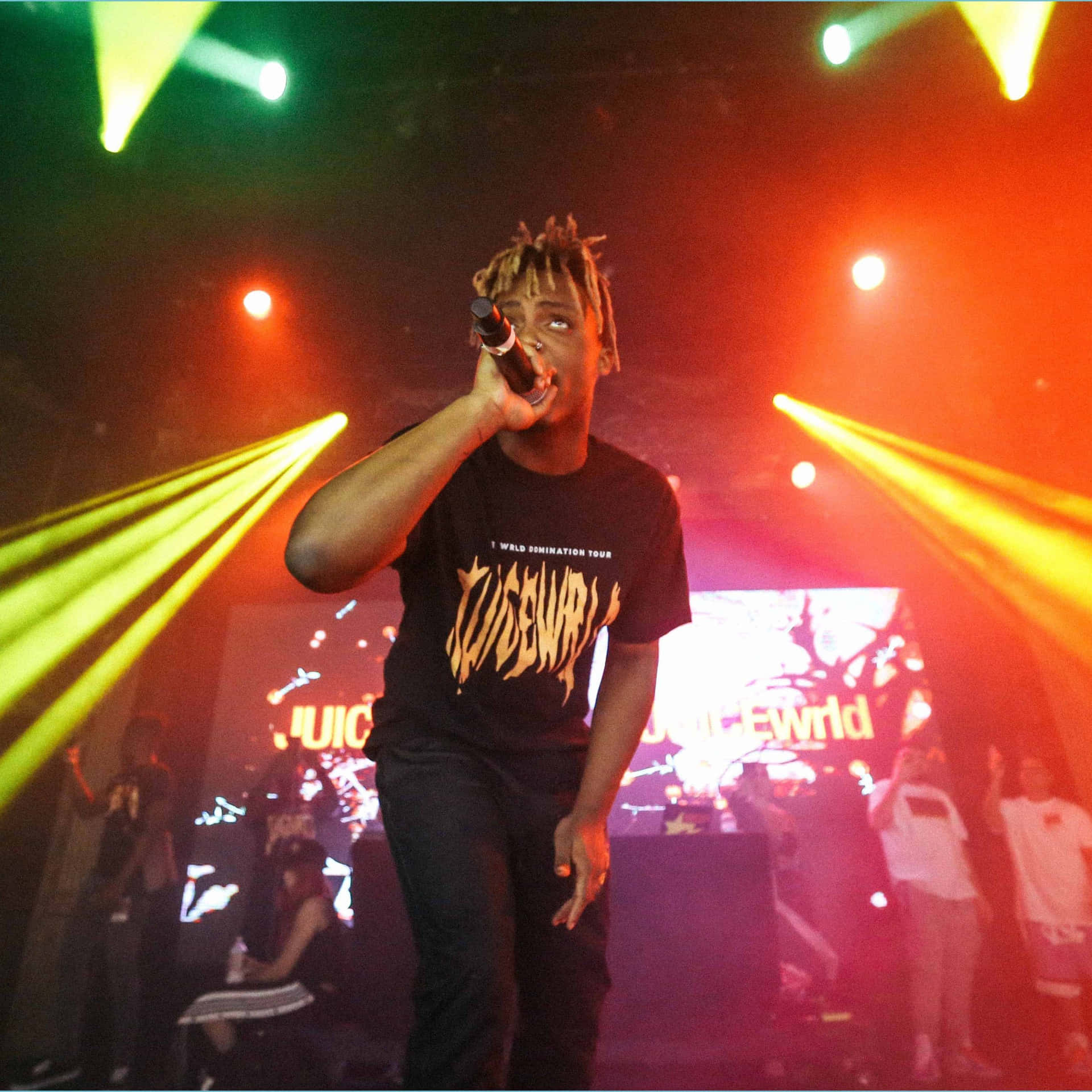 說唱歌手在舞台上表演，伴隨著五彩燈光和歡呼的人群。 — Juice Wrld 壁紙