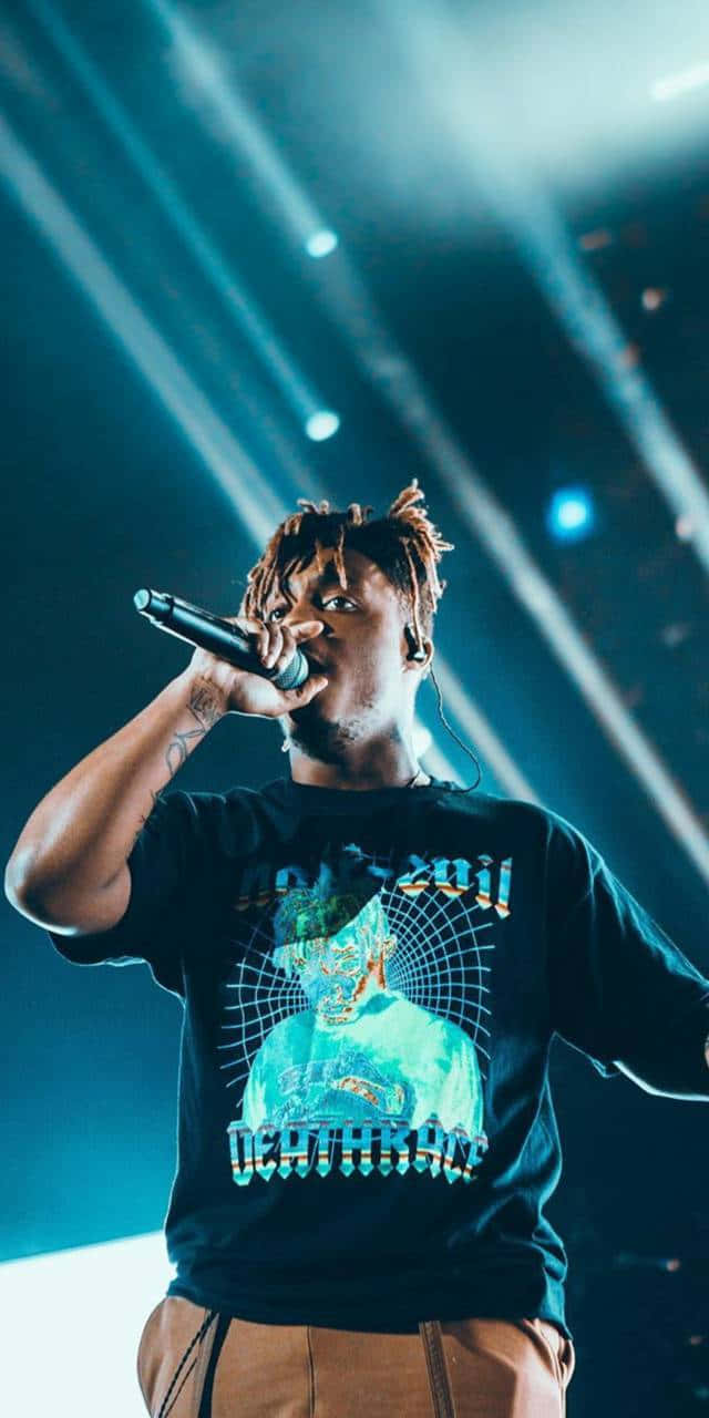 Rappers 桌布 壁紙 — 一位梳著辮子的說唱歌手在明亮的藍色舞台燈光下熱情地對著麥克風表演。