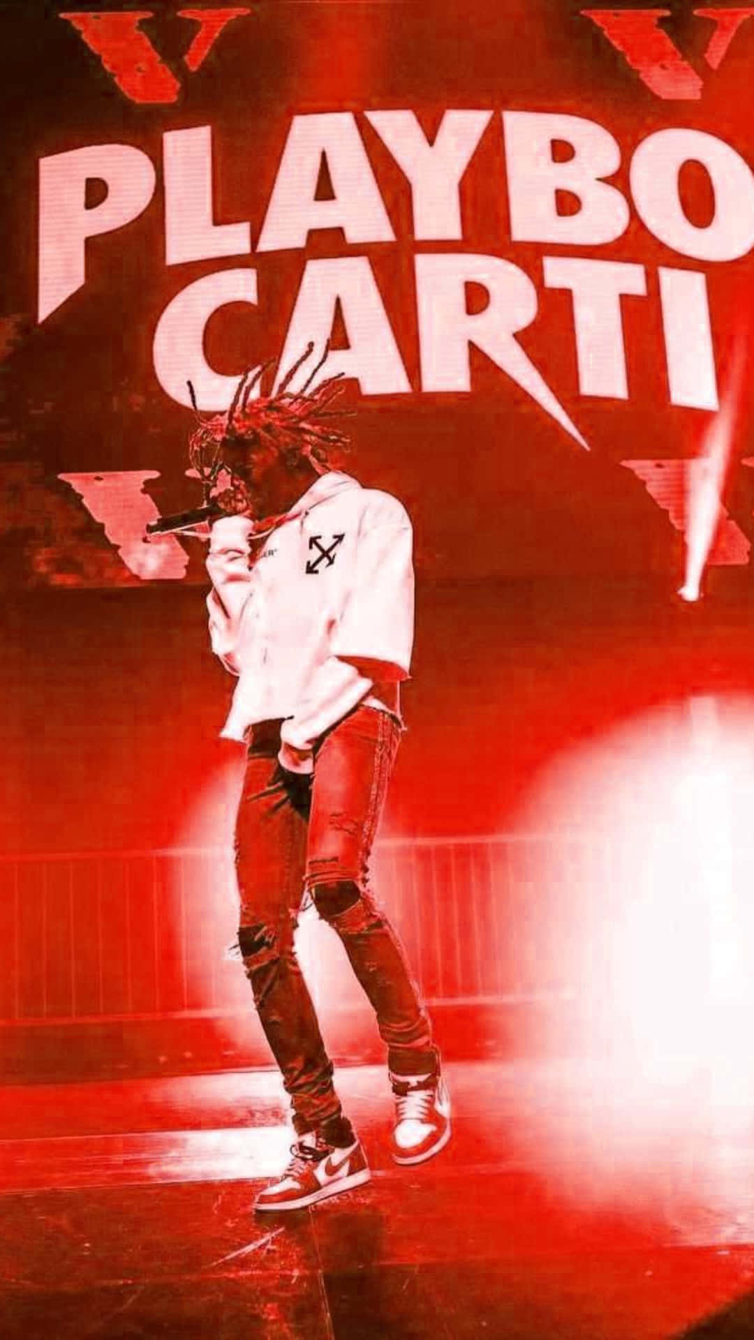 Playboi Carti iPhone 桌布 壁紙 — 一位梳著辮子的饒舌歌手在紅色燈光舞台上，在「PLAYBOI CARTI」文字下表演，身穿白色連帽衫和破洞牛仔褲。
