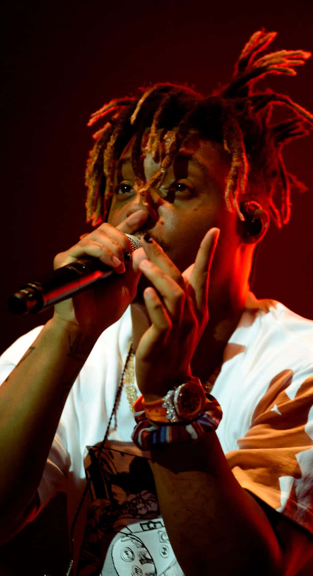 饒舌歌手在紅色燈光下於舞台上手持麥克風表演。 — Juice Wrld 壁紙