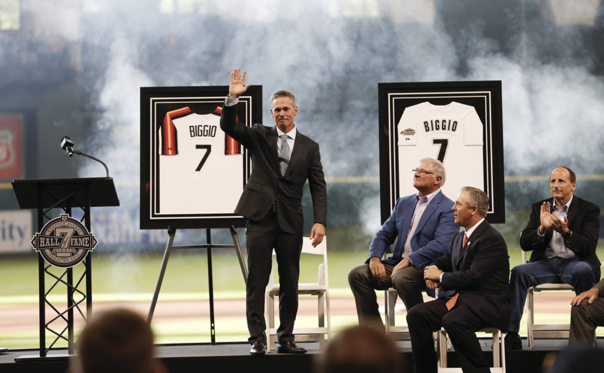 Craig Biggio 桌布 壁紙 — 一位棒球傳奇人物向球迷揮手，他的退役7號球衣在名人堂舞台上揭幕，伴有煙霧效果和鼓掌的貴賓。