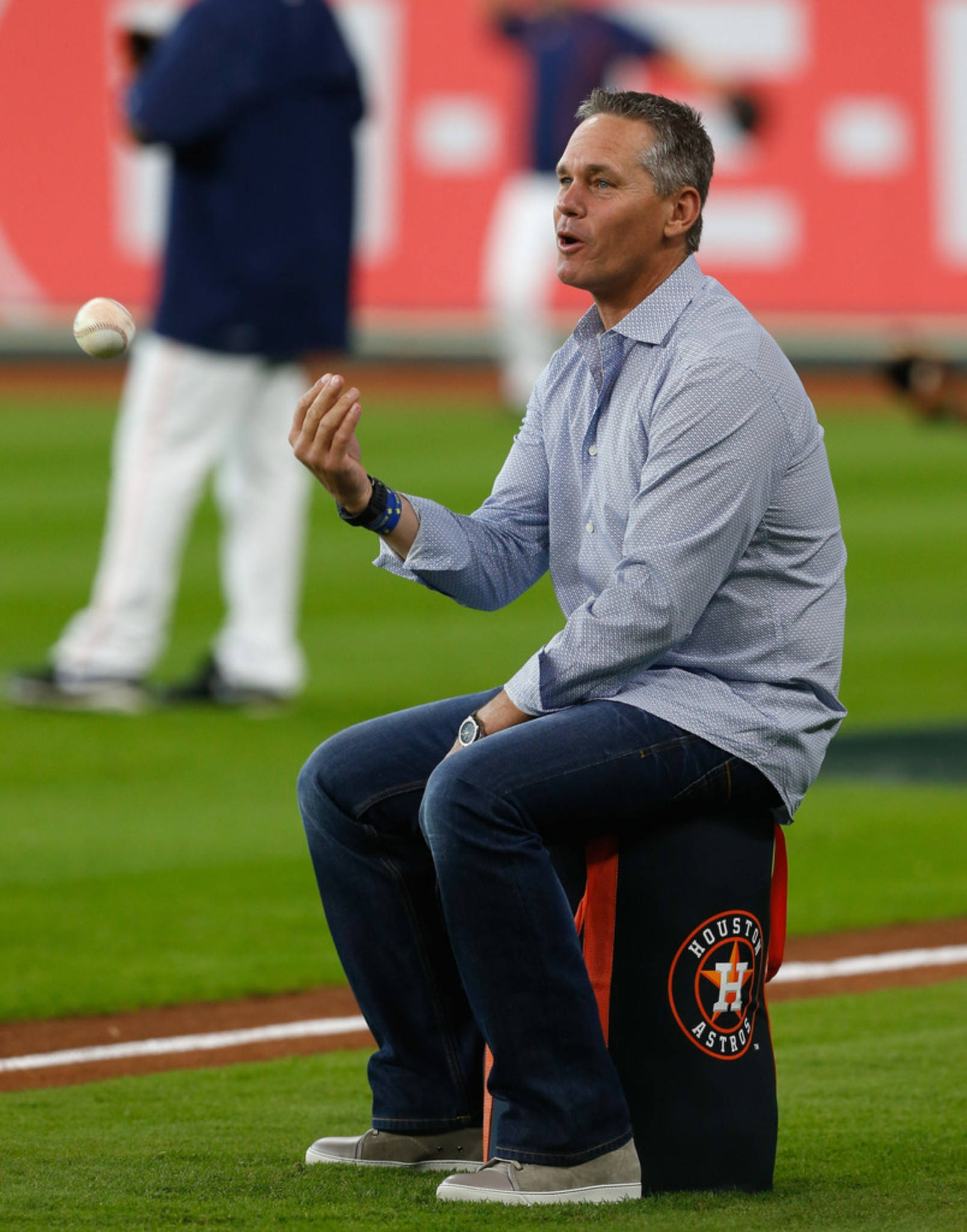 Craig Biggio 桌布 壁紙 — 一位棒球教練坐在球隊品牌的凳子上，一邊投球一邊在綠色場地上說話，身後有模糊的球員。