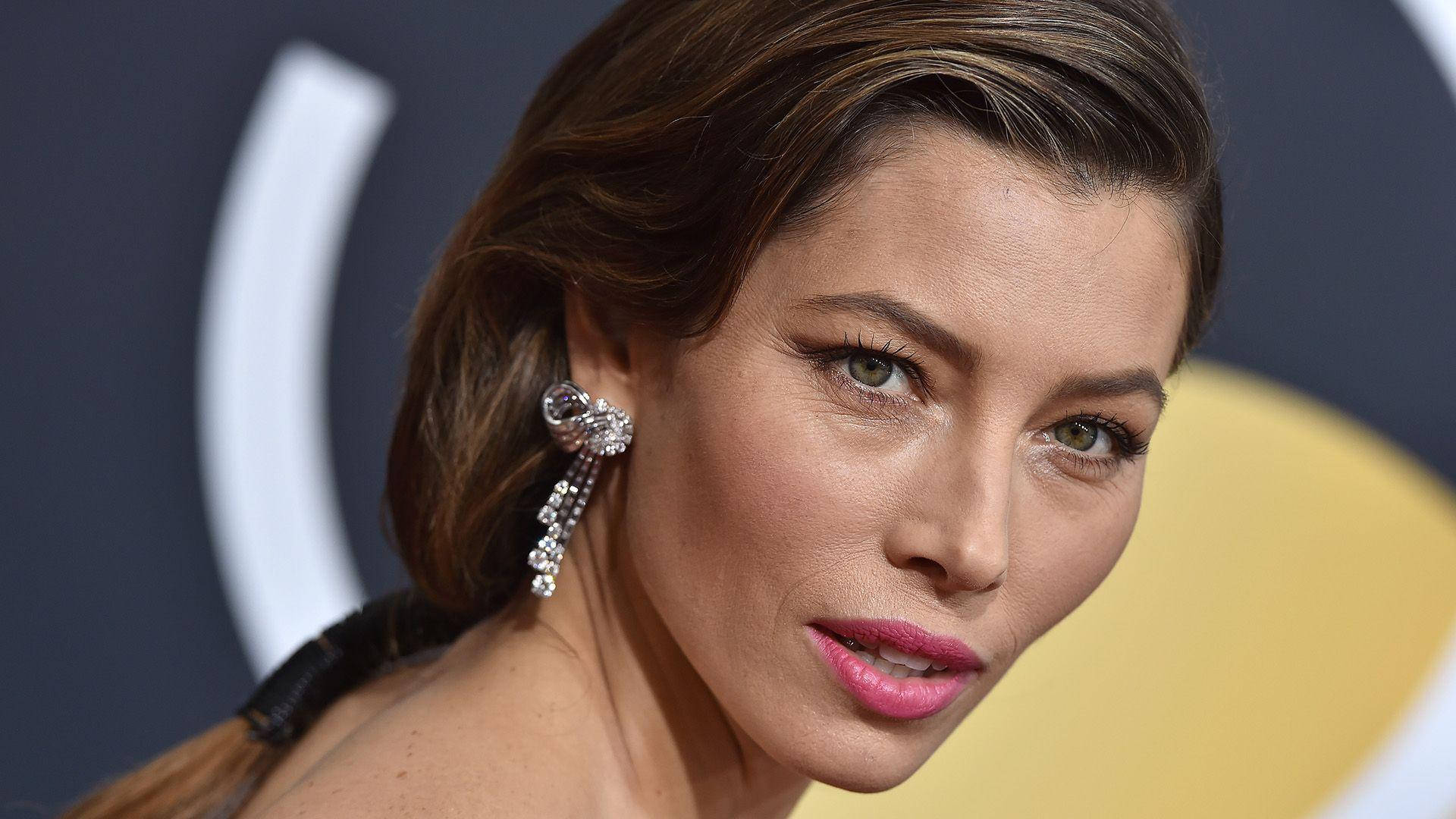 jessica biel 桌布 壁紙 — 一位棕色頭髮、塗著粉紅色唇膏的女性在華麗活動中佩戴閃爍鑽石耳環的特寫肖像。