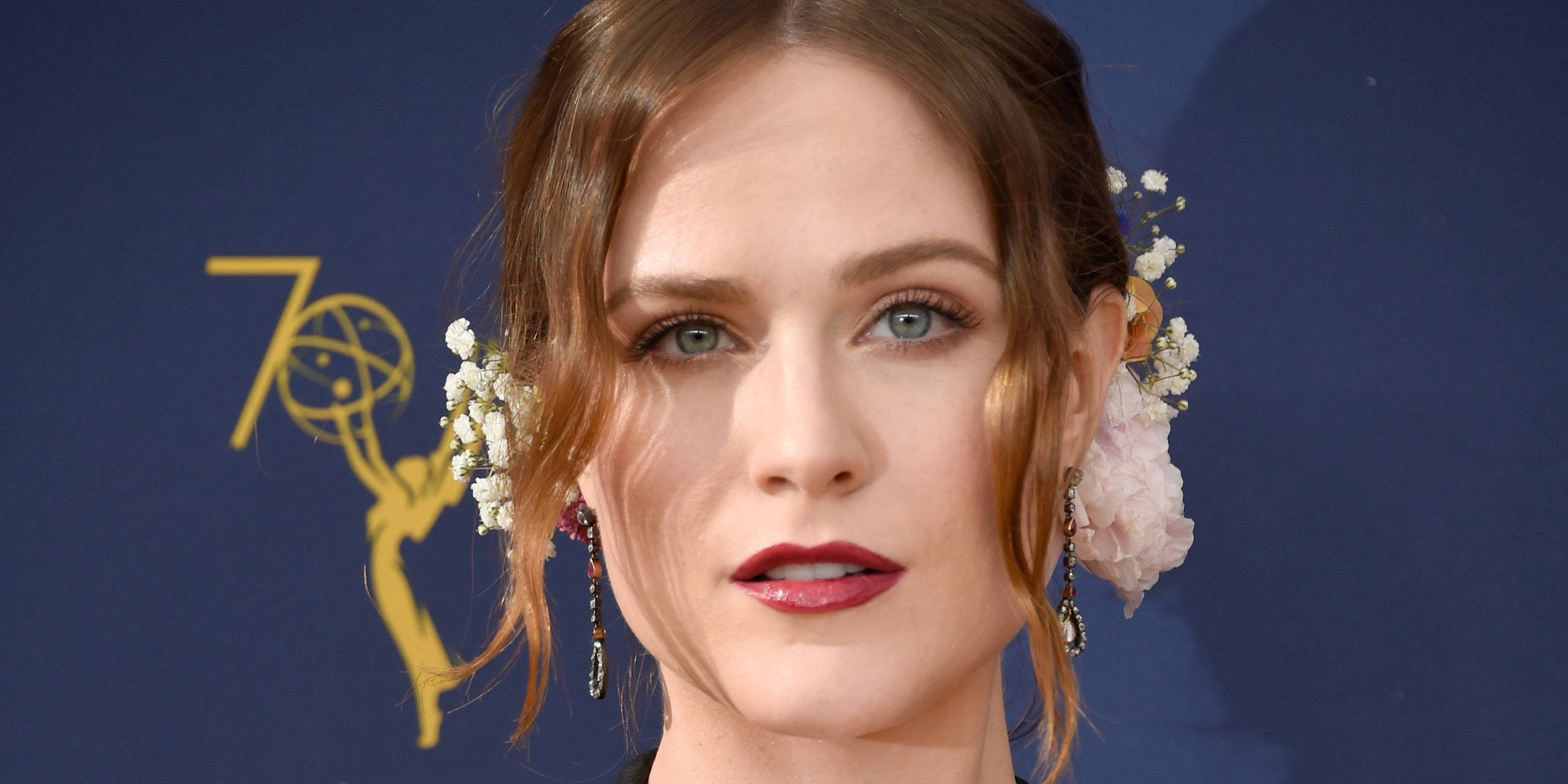 Celebrity 桌布 壁紙 — 一位棕色頭髮、戴著白色花朵和紅色唇膏的女性，在帶有金色艾美獎標誌的藍色背景前擺姿勢。