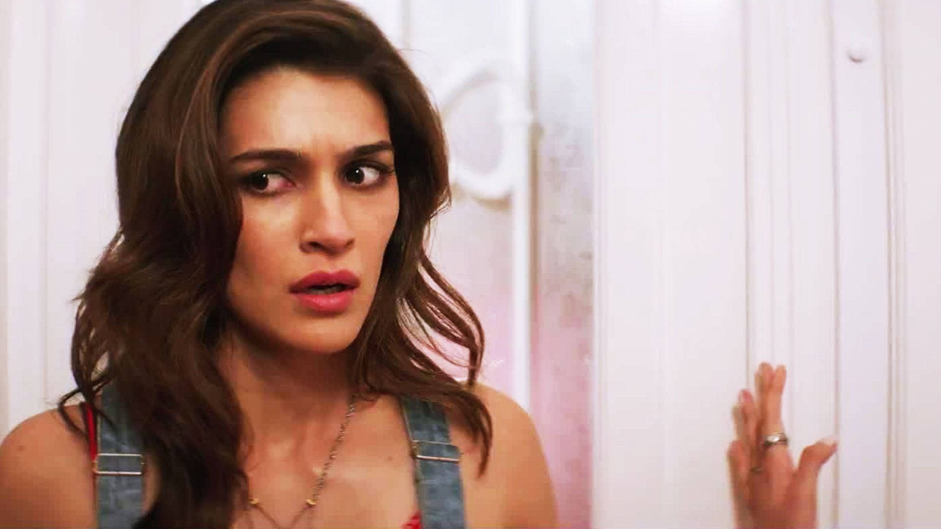 Kriti 桌布 壁紙 — 一位棕色頭髮、身穿牛仔布工裝褲的女性在觸摸白色門時顯得吃驚。