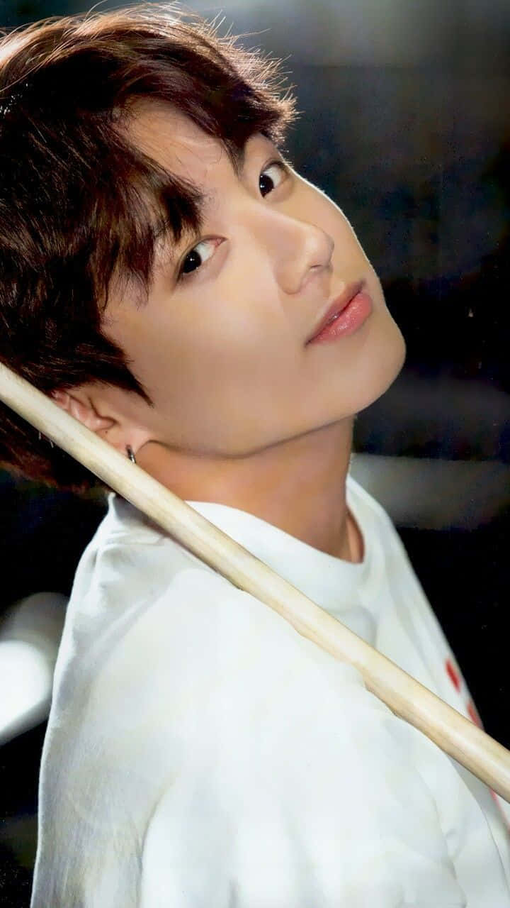 Jungkook 桌布 壁紙 — 一位棕色頭髮、身穿白襯衫的年輕男子，肩上扛著一根木棍，向上凝視。