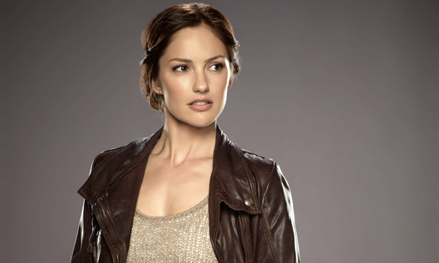 minka kelly 桌布 壁紙 — 一位棕色頭髮的女性在灰色攝影棚背景前，穿著棕色皮外套，內搭閃亮上衣。