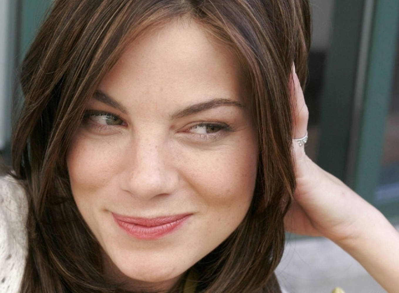 Michelle Monaghan 桌布 壁紙 — 一位棕色頭髮的女性將手放在臉部附近溫柔微笑的特寫肖像。