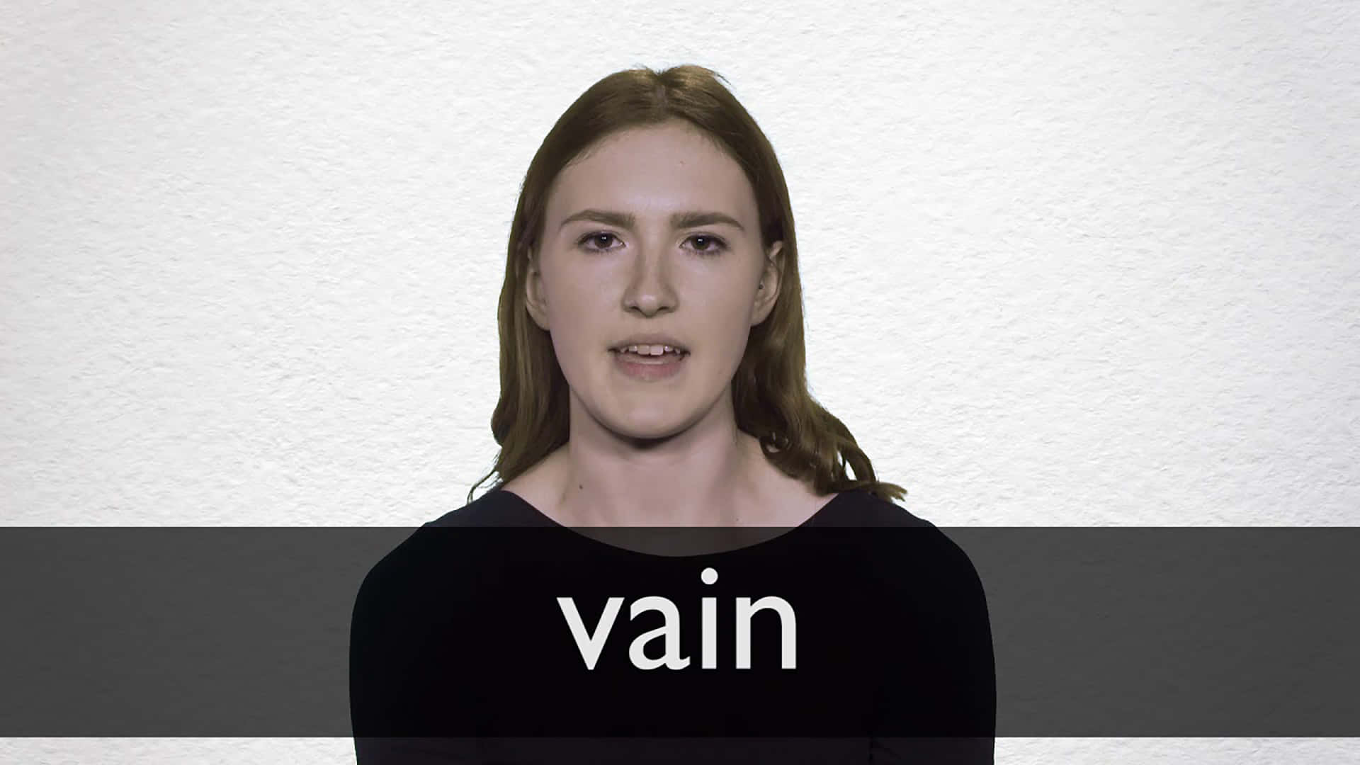 女性穿著黑色襯衫，胸前有 vain 字樣，背景為白色牆壁。 — 影片 GIF 壁紙