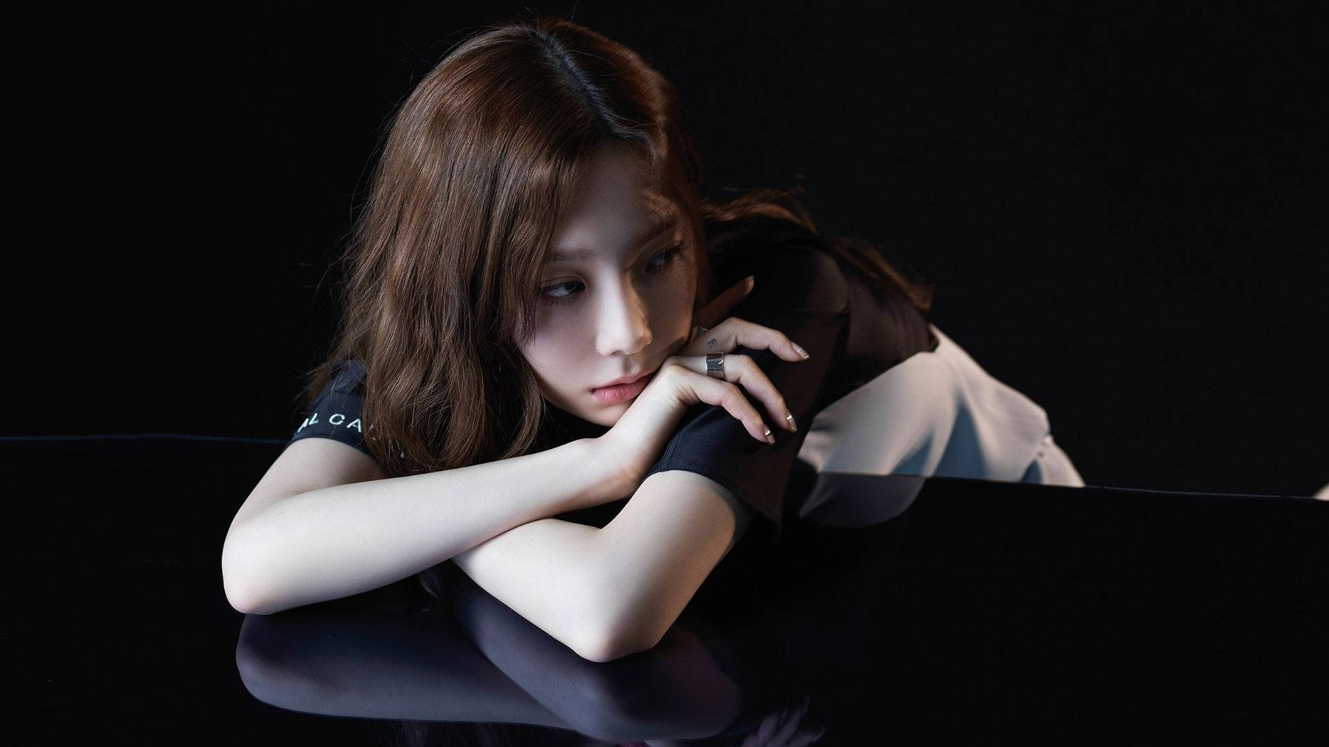 Taeyeon 桌布 壁紙 — 一位棕色頭髮的年輕女子在光線昏暗的錄音室裡，將下巴擱在雙臂上，放在光亮的黑色鋼琴上。