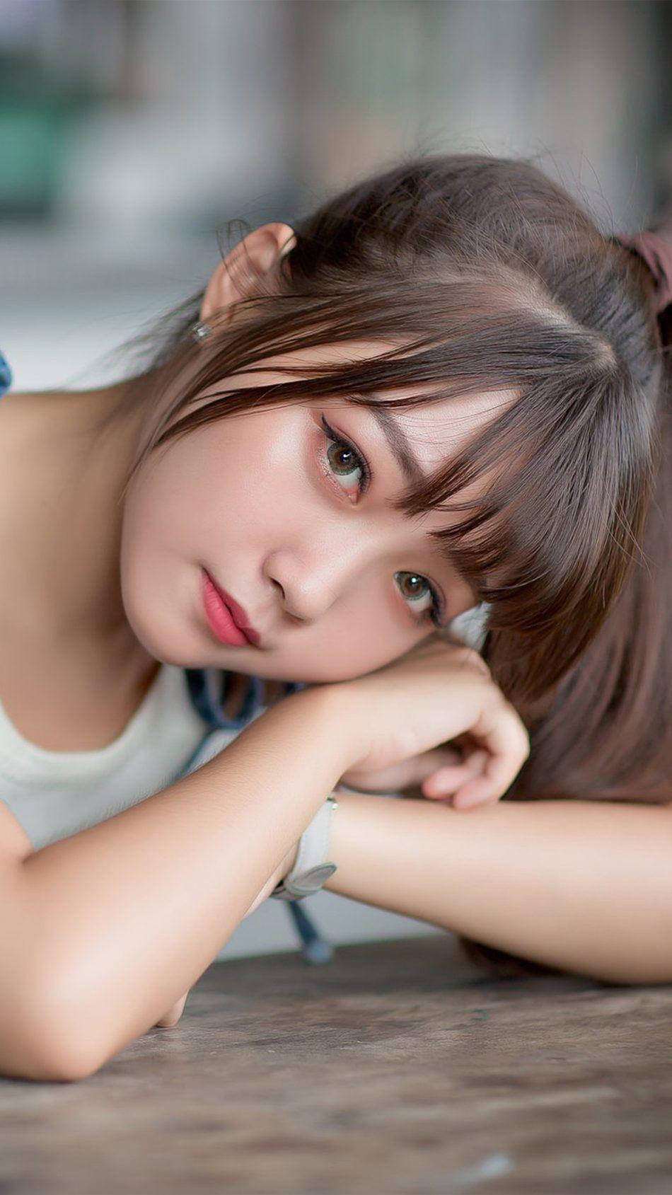 Cute Girl 桌布 壁紙 — 一位棕色頭髮的年輕女子將下巴擱在木質表面上的雙臂上，溫柔地凝視著鏡頭。