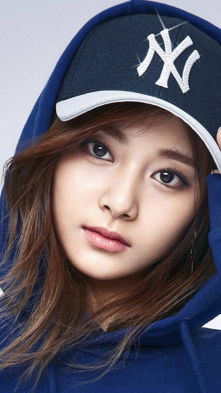 Beautiful Woman 桌布 壁紙 — 一位棕色頭髮的年輕女性穿著藍色連帽衫和深藍色紐約洋基隊帽子，直視鏡頭。