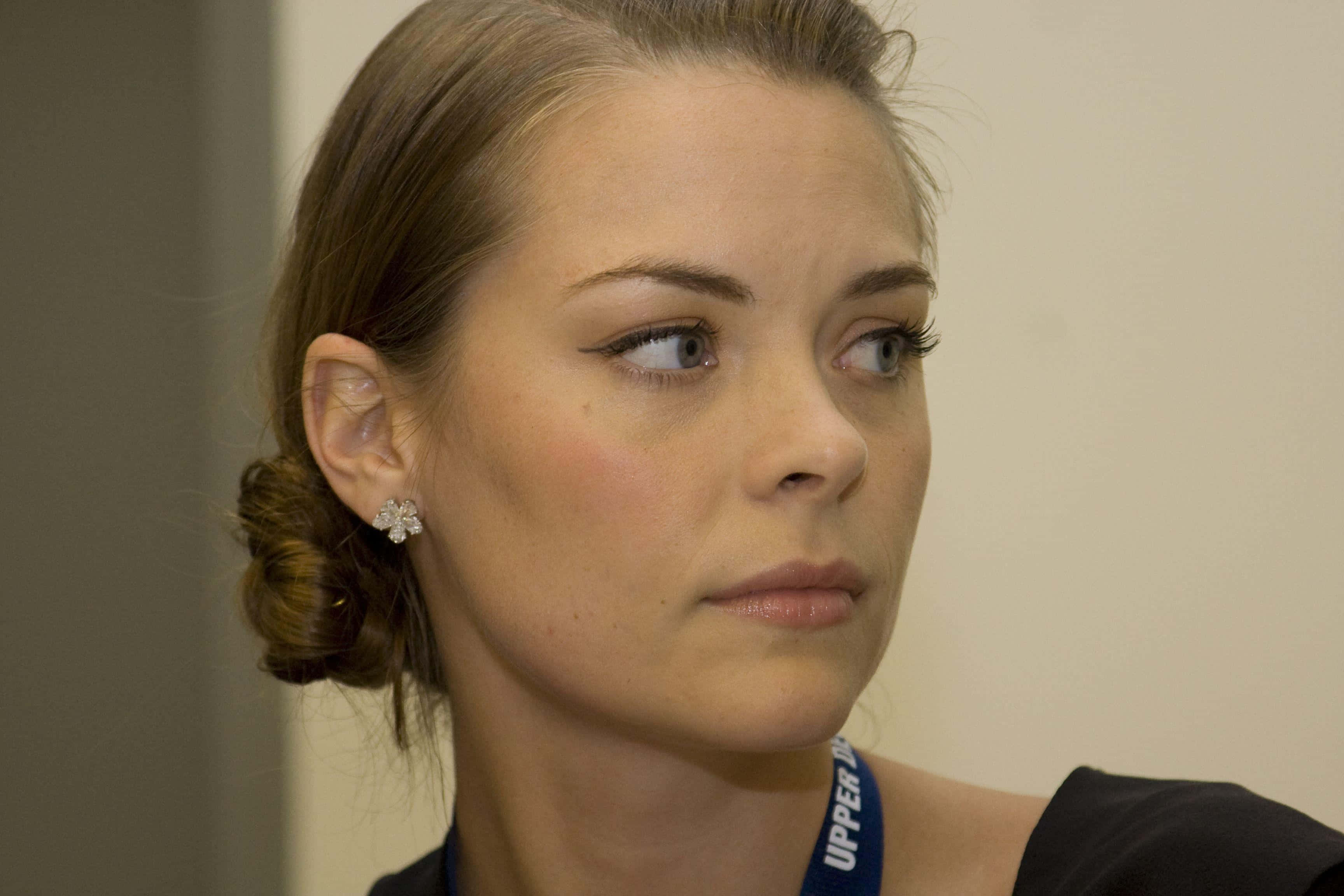 Jaime King 桌布 壁紙 — 一位棕色頭髮盤成髮髻、戴著藍色掛繩和花卉耳環的女性側臉特寫。