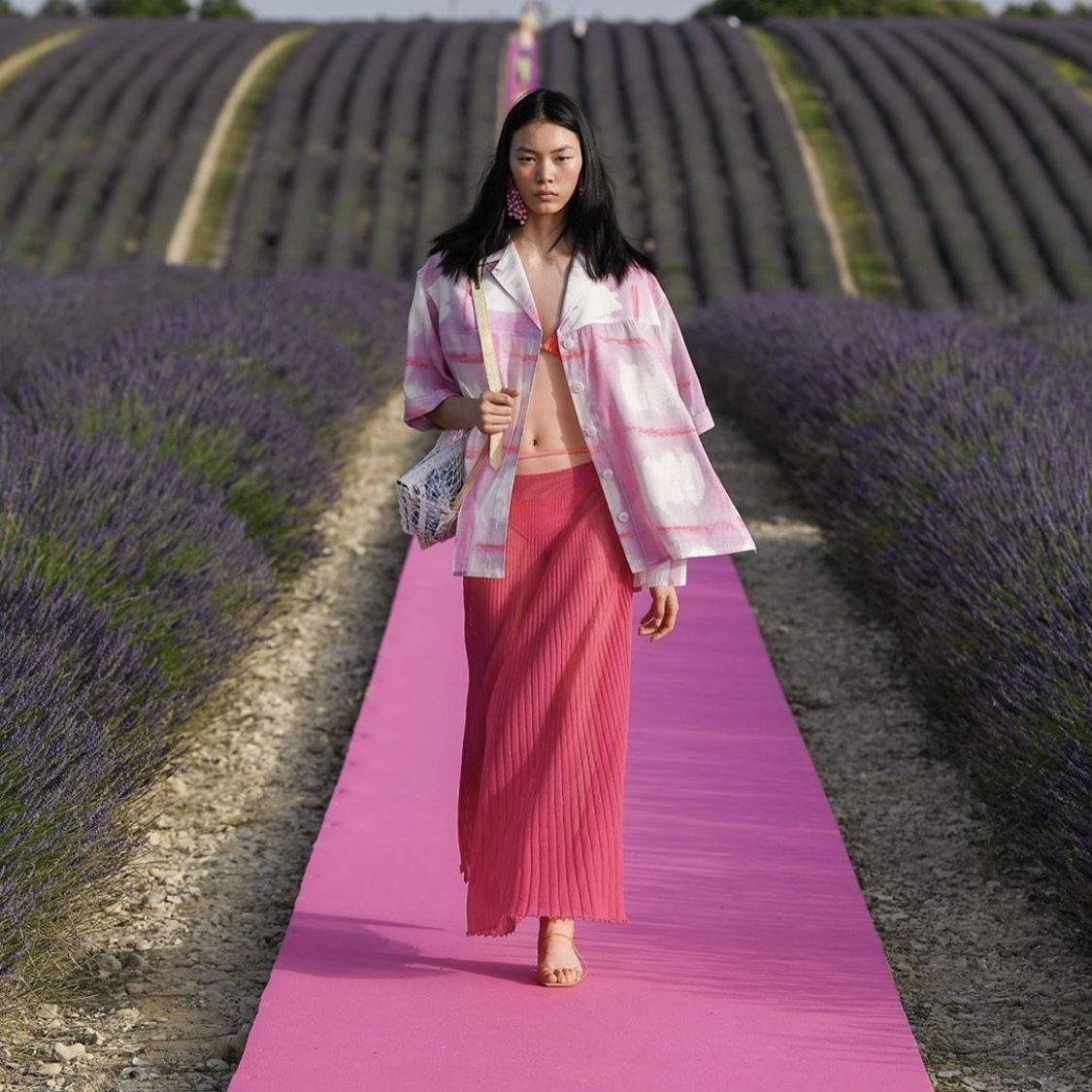 Fashion Model 桌布 壁紙 — 一位模特兒自信地走在充滿活力的粉紅色T台上，穿過一排排紫色的薰衣草田，在明亮的日光下。