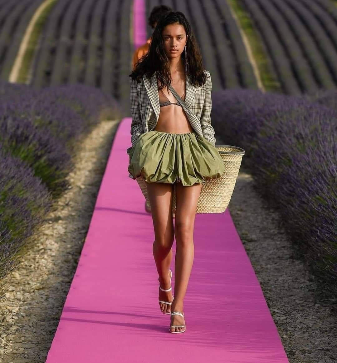Fashion Model 桌布 壁紙 — 一位模特兒自信地走在充滿活力的粉紅色伸展台上，穿過一排排盛開的薰衣草田，在明亮的日光下。