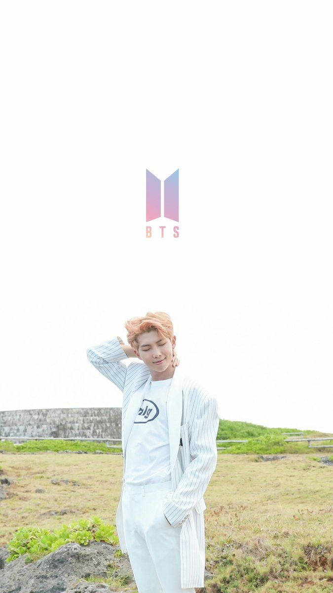 BTS 桌布 壁紙 — 一位橙色頭髮的年輕男子穿著白色服裝，在明亮的天空下放鬆地站在草地上，上方漂浮著BTS標誌。