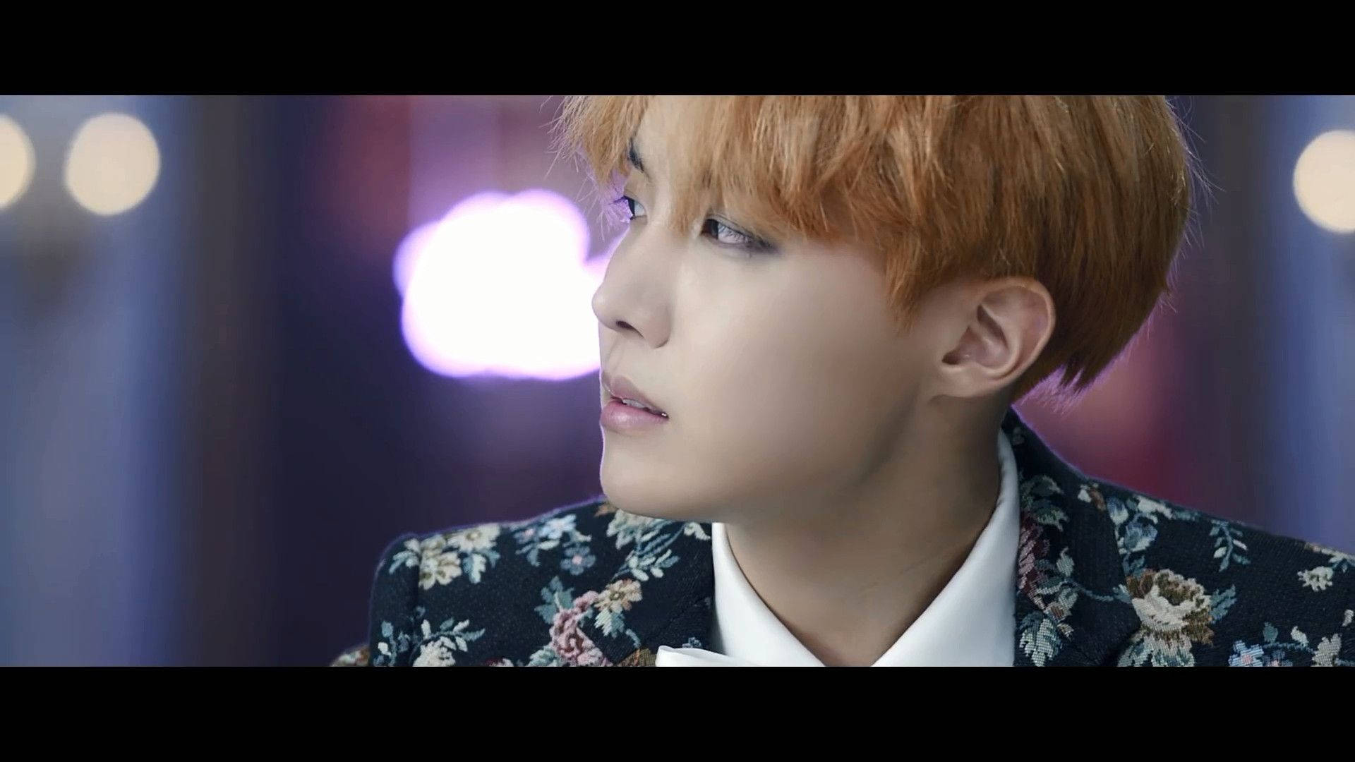 jhope 桌布 壁紙 — 一位橙髮年輕男子側面沉思，身穿花卉圖案西裝外套，背景是柔和模糊的散景。