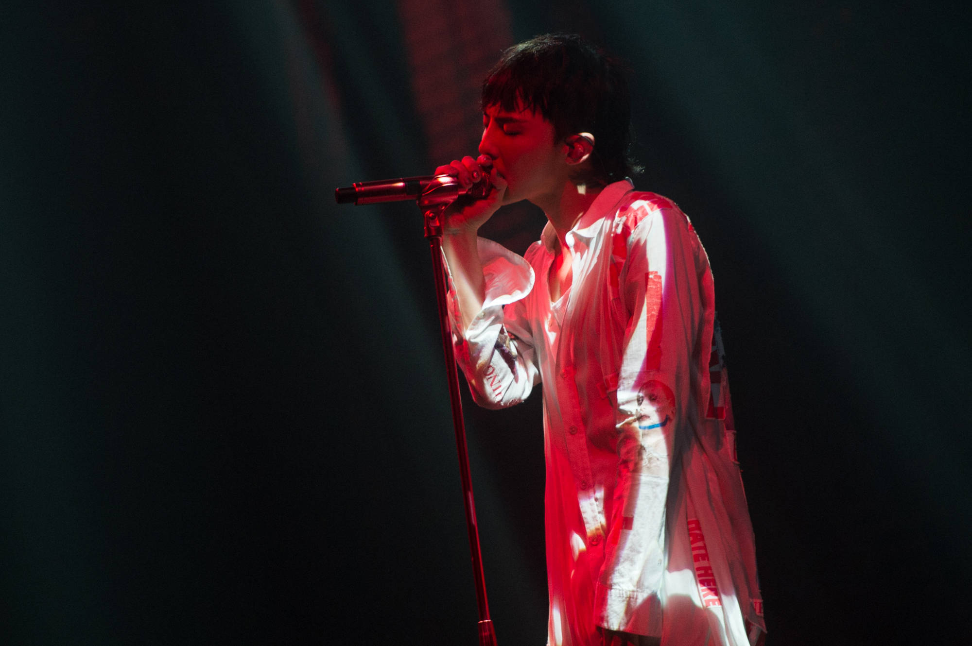 G-dragon 桌布 壁紙 — 一位歌手在戲劇性的紅色舞台燈光下熱情表演，身穿帶有紅色污漬的白襯衫。