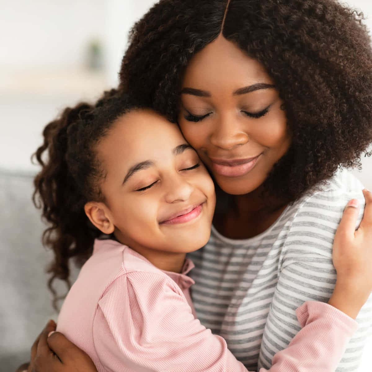 Mother Love 桌布 壁紙 — 一位母親和女兒在柔和光線的室內環境中，閉上眼睛，帶著溫柔的微笑，分享一個溫馨的擁抱。