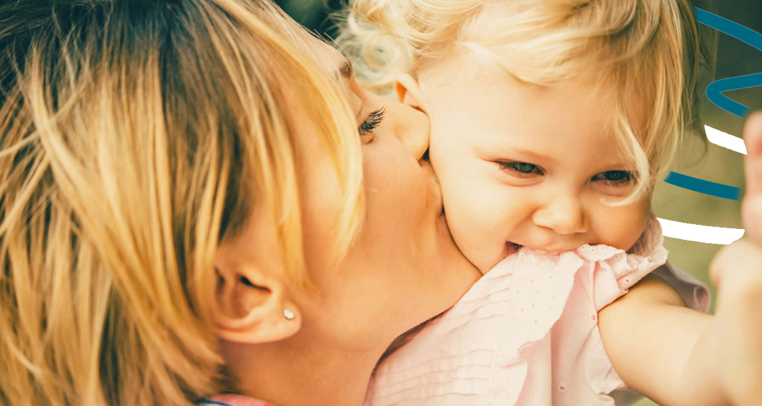 Mother Love 桌布 壁紙 — 一位母親親吻她微笑的女嬰的臉頰，而孩子頑皮地咬著粉紅色的袖子。