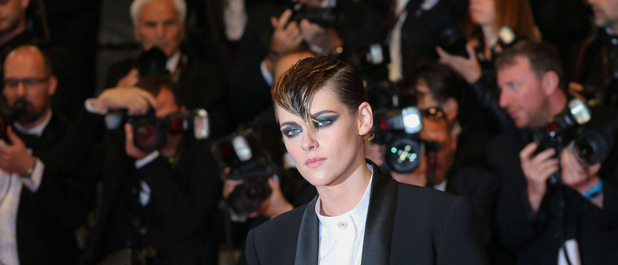 Kristen 桌布 壁紙 — 一位沉著自信、妝容大膽的女性在閃光燈和攝影師的包圍下走過紅地毯。
