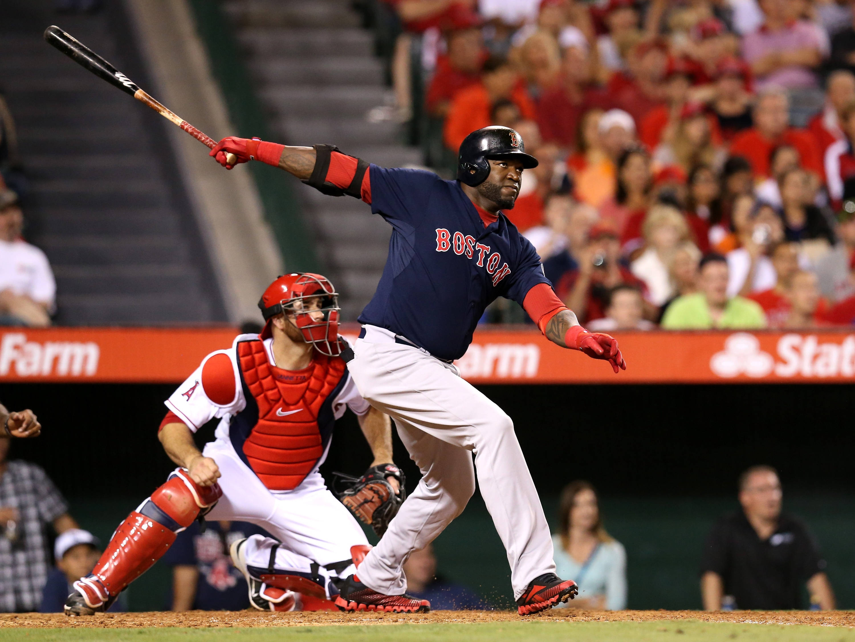 Red Sox 桌布 壁紙 — 一位波士頓棒球選手在夜間比賽中強力揮棒，捕手蹲在他身後。