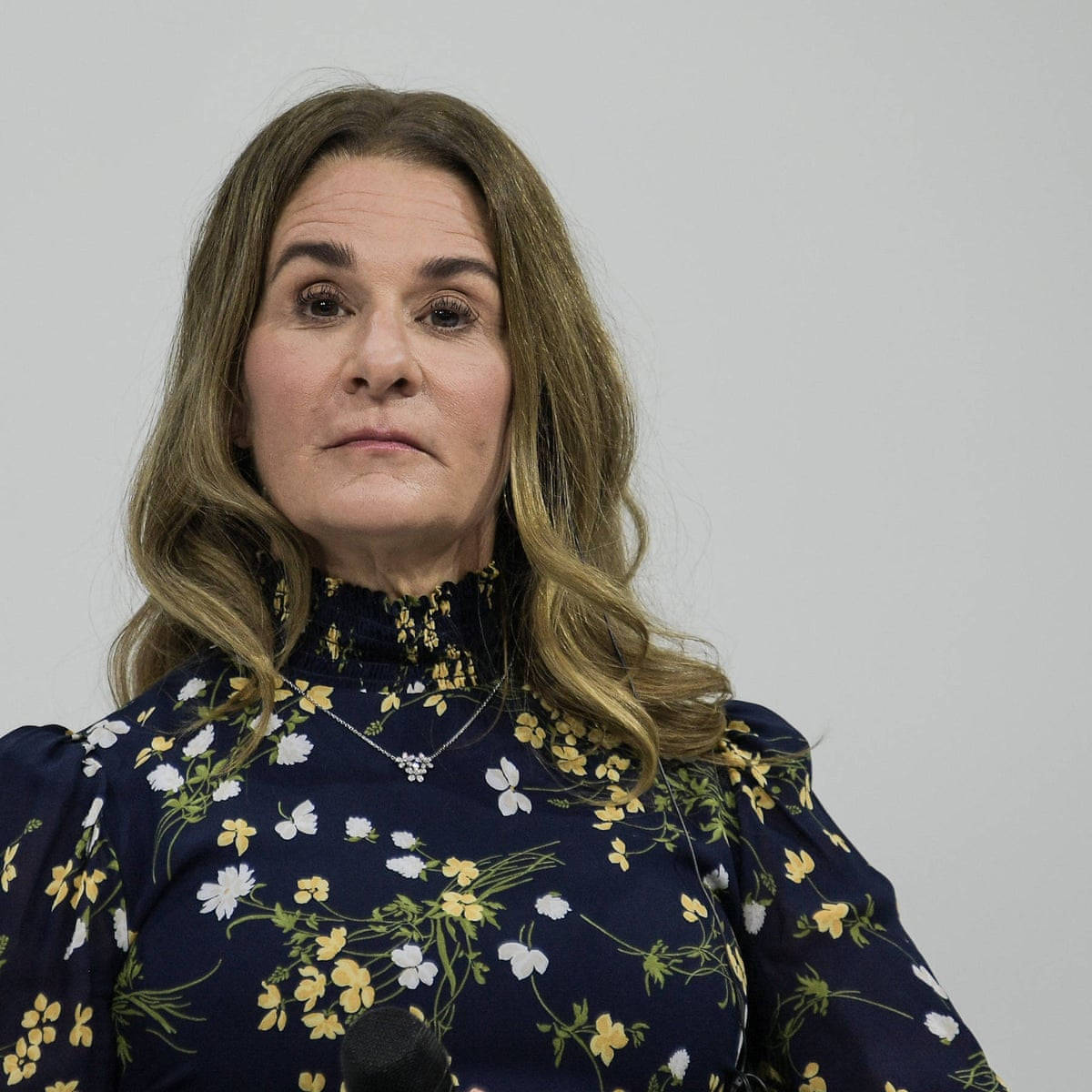 身穿花卉襯衫的女性，表情嚴肅地站在麥克風前 — Microsoft 壁紙