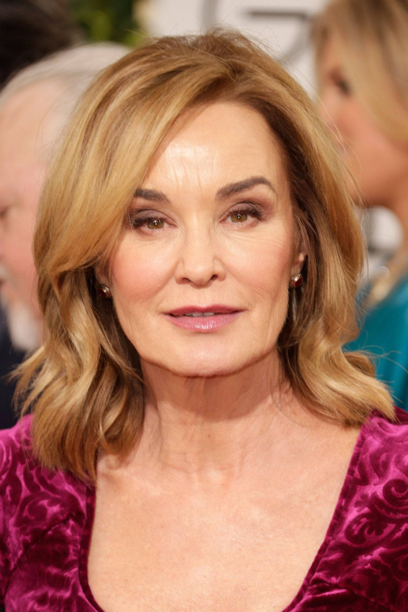 Jessica Lange 桌布 壁紙 — 一位波浪金髮女性在正式活動中穿著深紫色天鵝絨上衣的特寫肖像。