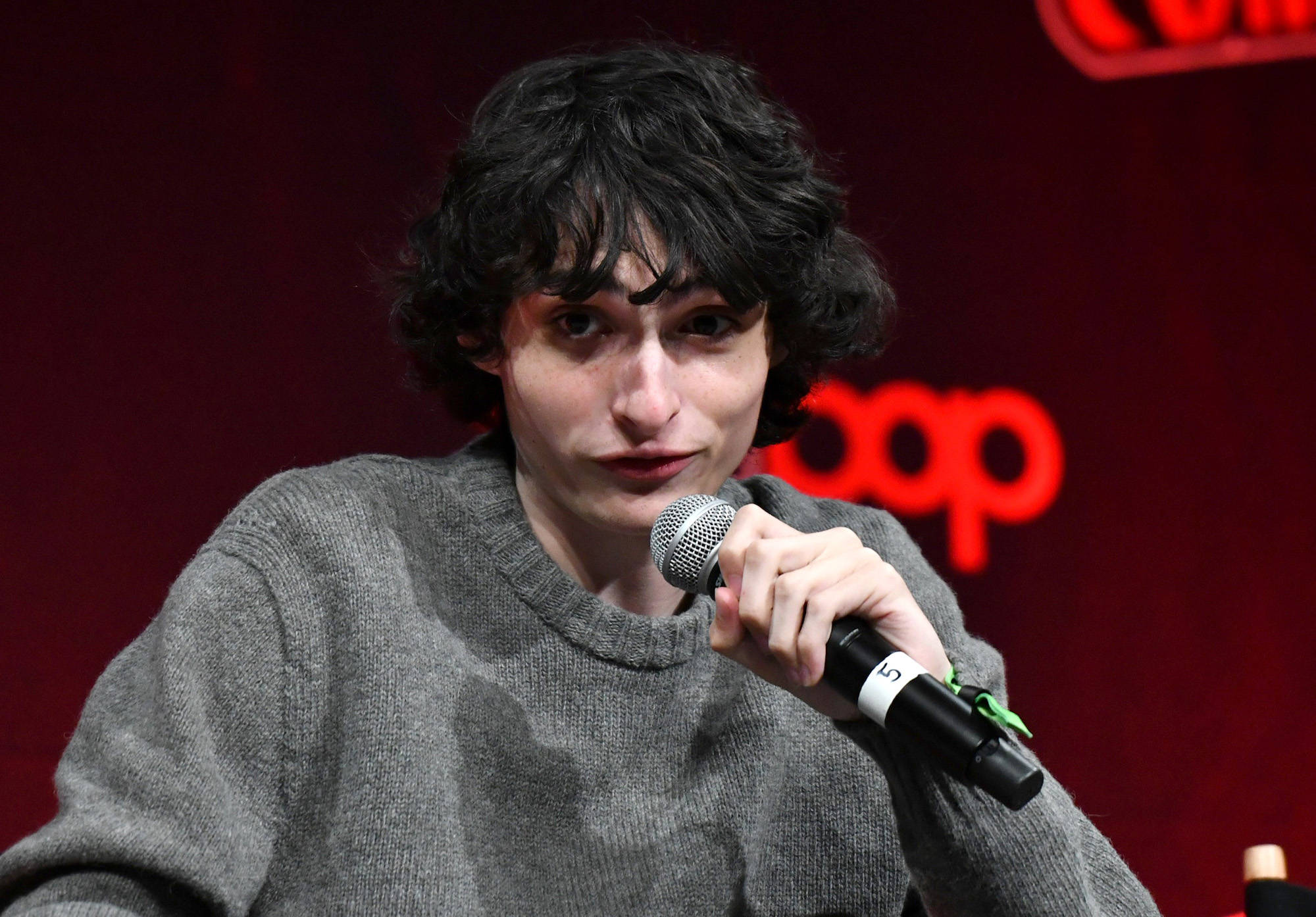 Celebrity 桌布 壁紙 — 一位深色捲髮的年輕男子在紅色背景的活動中對著麥克風說話。