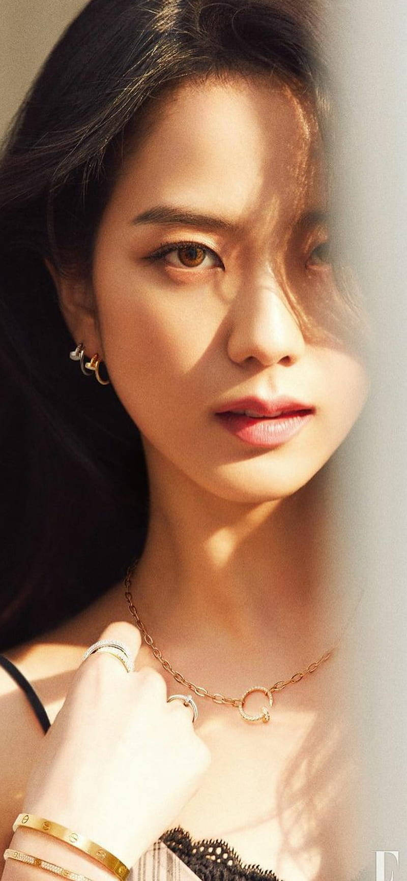 Jisoo Cute 桌布 壁紙 — 一位深色頭髮、佩戴金色珠寶的女性透過薄紗窗簾溫柔地凝視，溫暖的陽光突顯了她的五官。