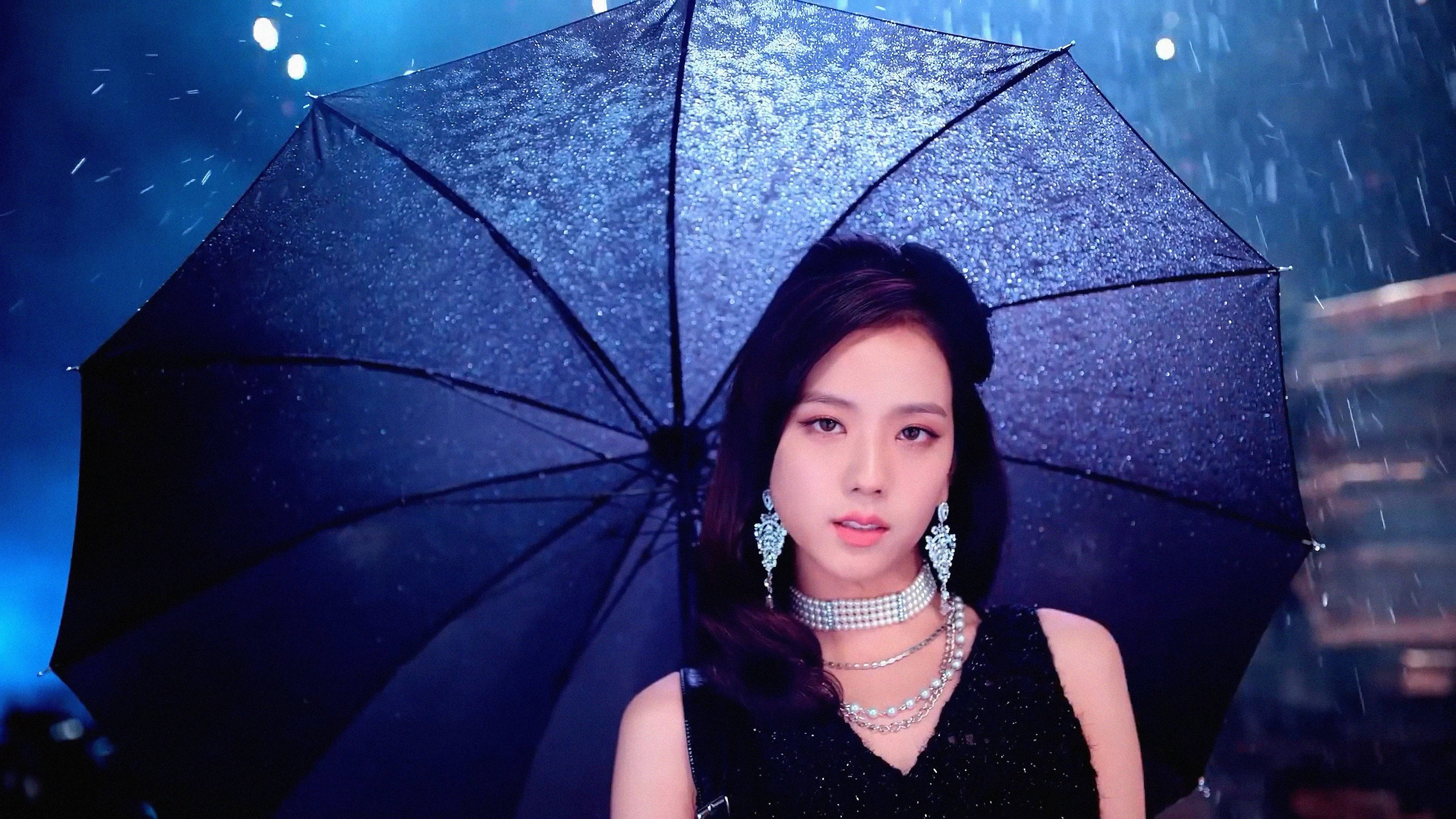 佩戴優雅珠寶的女性在夜雨中手持閃閃發光的黑色雨傘。 — 智秀 GIF 壁紙