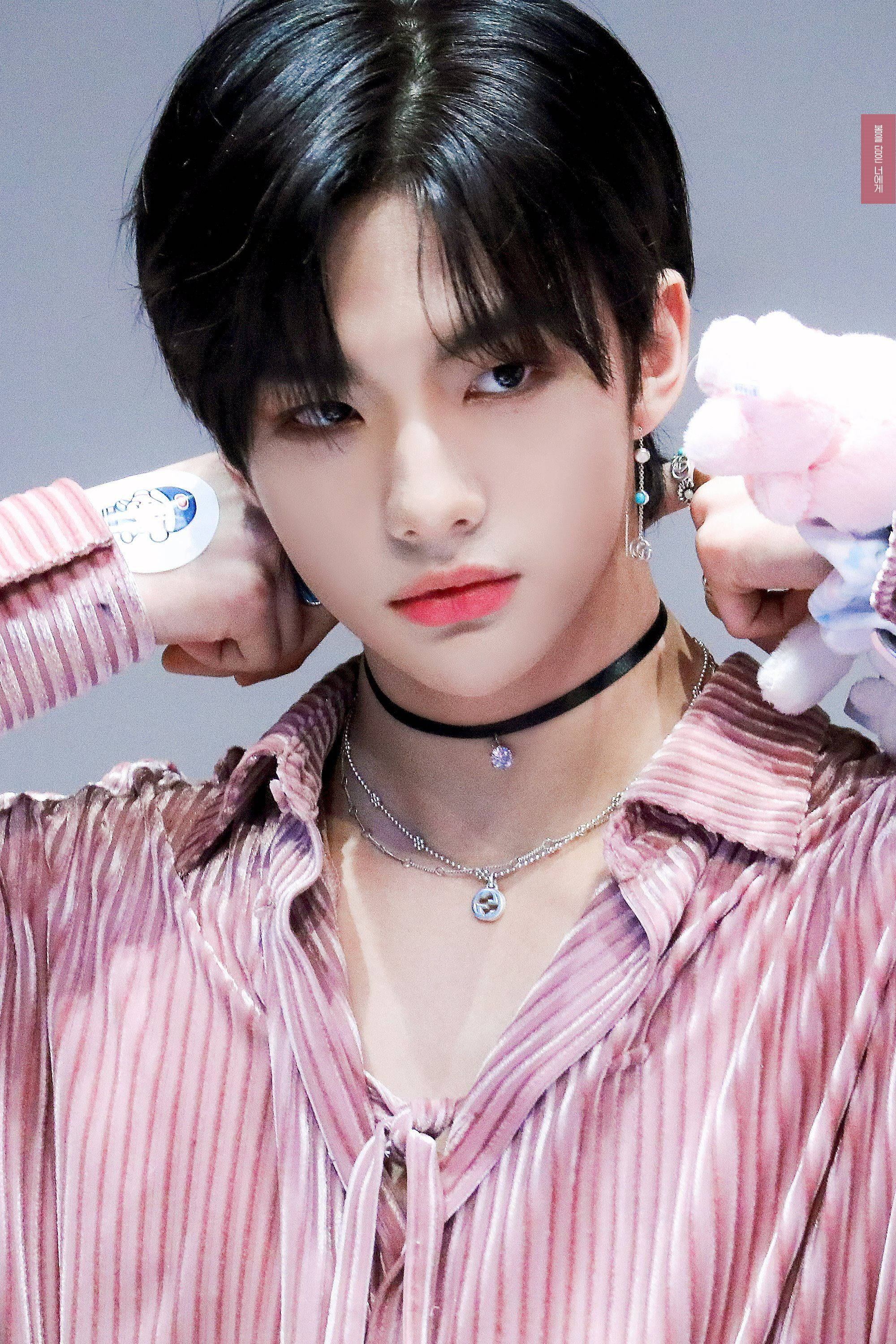 Stray Kids 桌布 壁紙 — 一位深色頭髮、化著大膽妝容的年輕男子，身穿粉紅色條紋襯衫，抱著毛絨玩具。