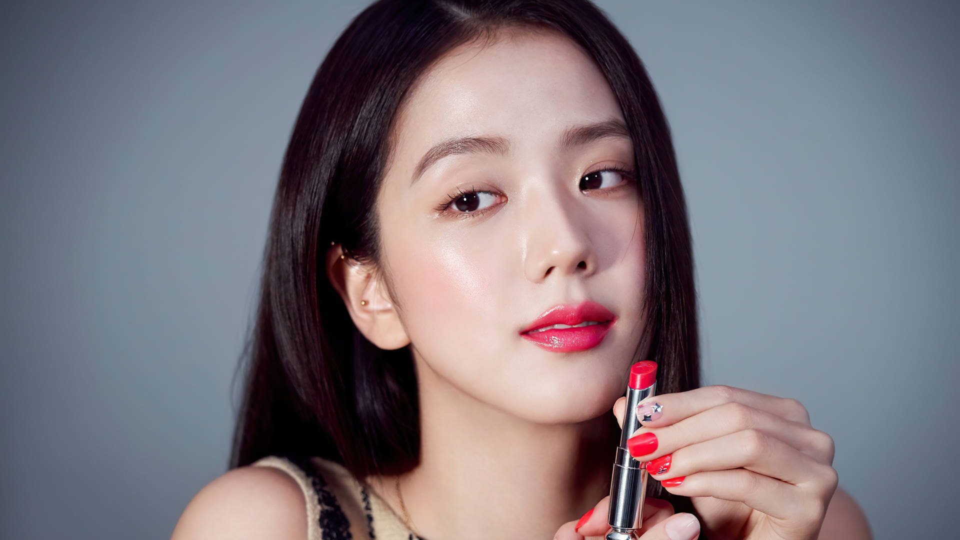 女性在灰色背景前拿著紅色口紅，搭配紅色指甲。 — 智秀 GIF 壁紙