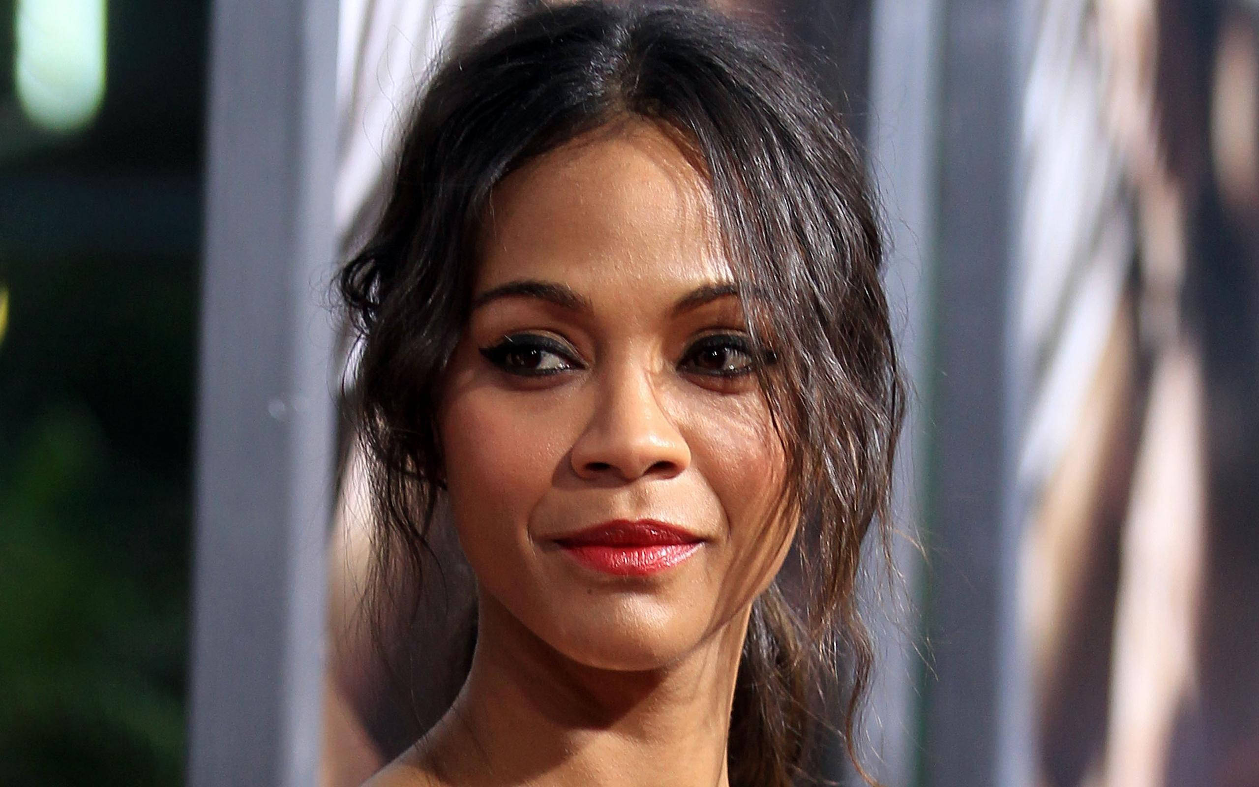 Zoe Saldana 桌布 壁紙 — 一位深色頭髮、塗著紅色唇膏的女性特寫肖像，直視鏡頭，帶著微妙的微笑。
