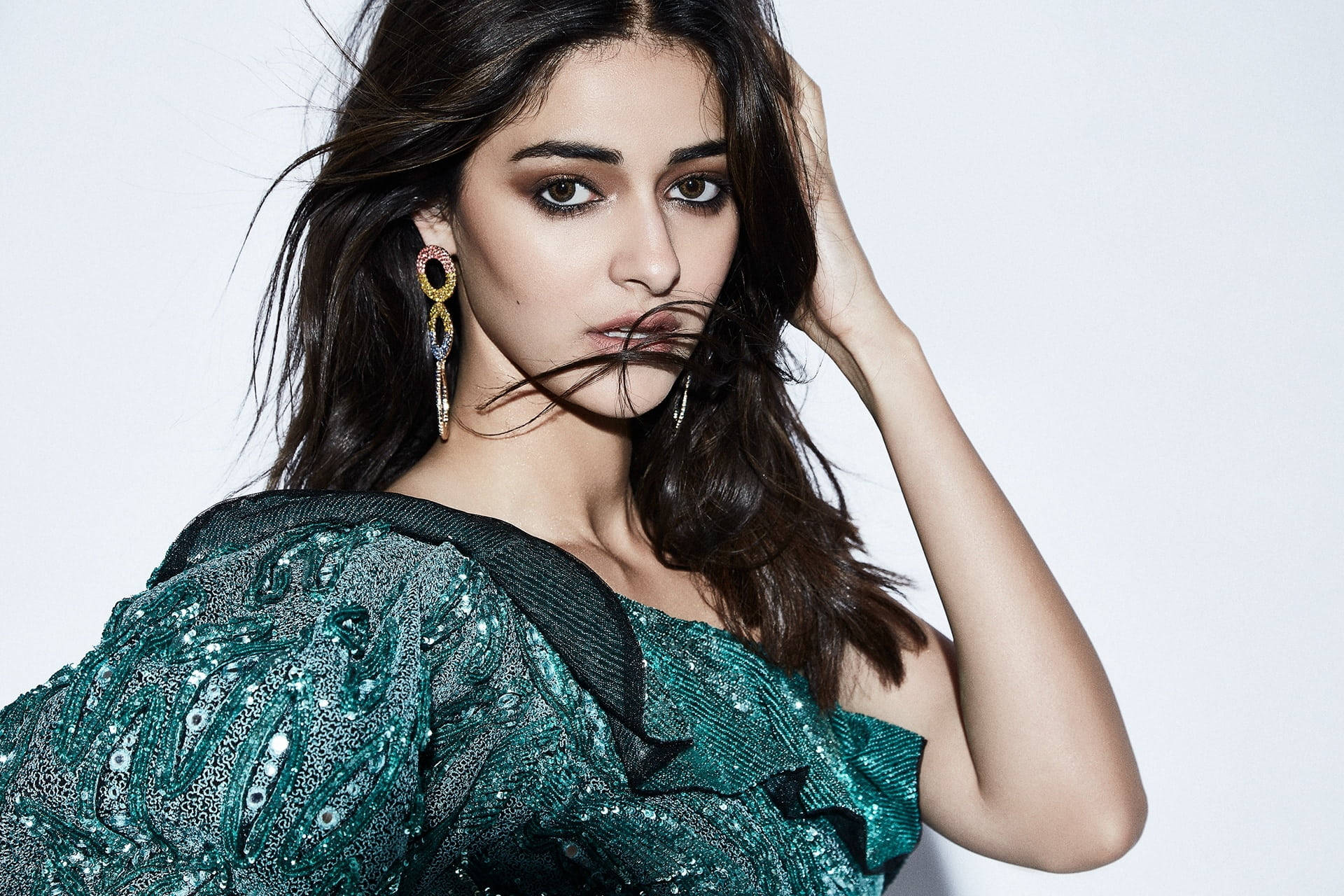 Celebrity 桌布 壁紙 — 一位深色頭髮、妝容大膽的女性，在純白色背景前穿著閃閃發光的綠色亮片上衣。