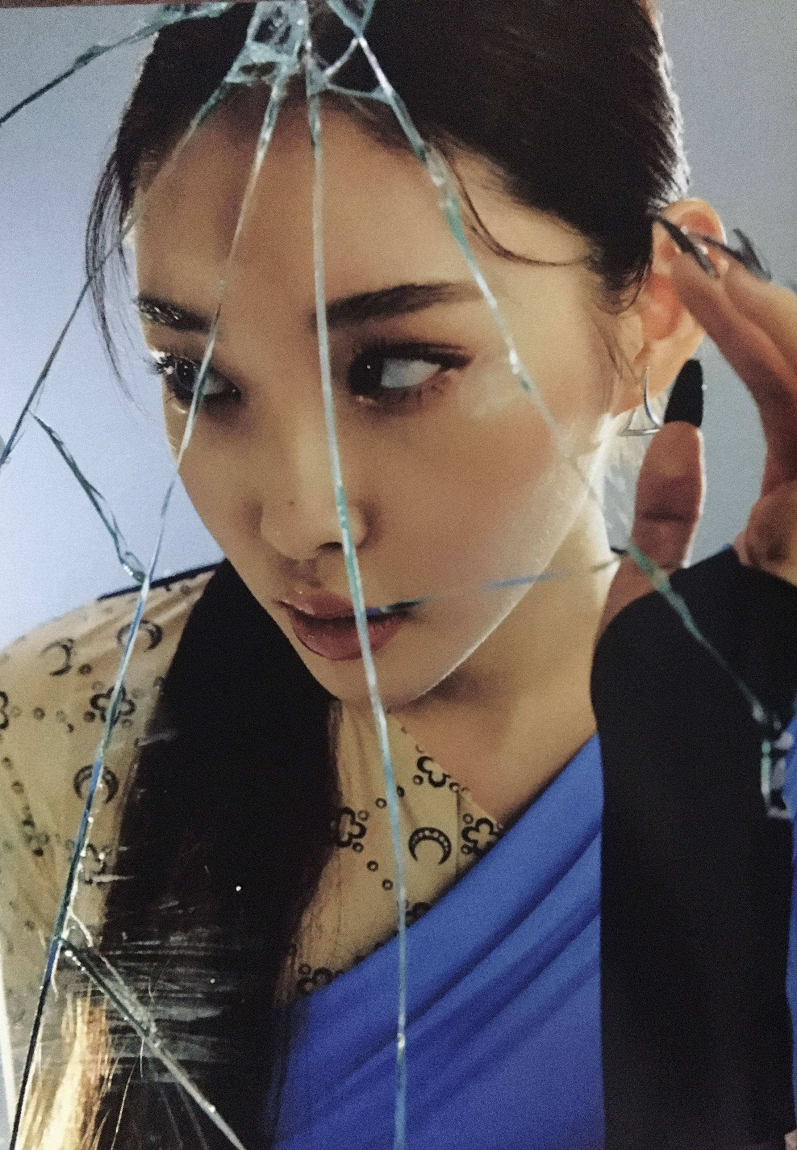 Chungha 桌布 壁紙 — 一位深色頭髮、妝容大膽的女性，透過碎裂的玻璃凝視，同時調整她的耳環。