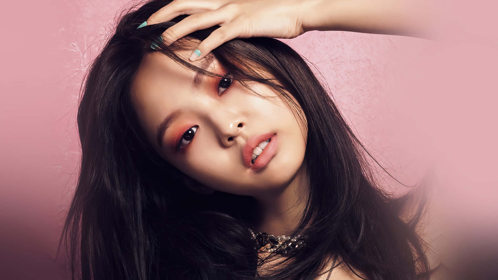 BLACKPINK 桌布 壁紙 — 一位深色頭髮、妝容大膽的年輕女性，在柔軟的粉紅色紋理背景上凝視著。