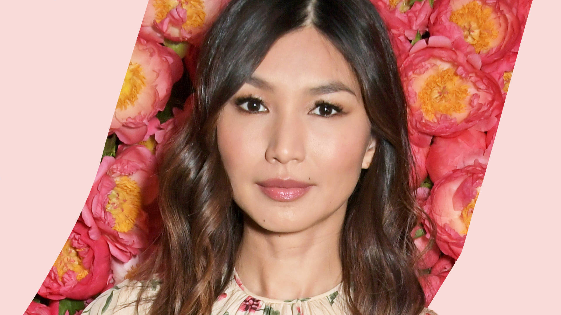 Gemma Chan 桌布 壁紙 — 一位深色頭髮、妝容柔和的女人，在充滿活力的粉紅色牡丹花卉背景下平靜地凝視。