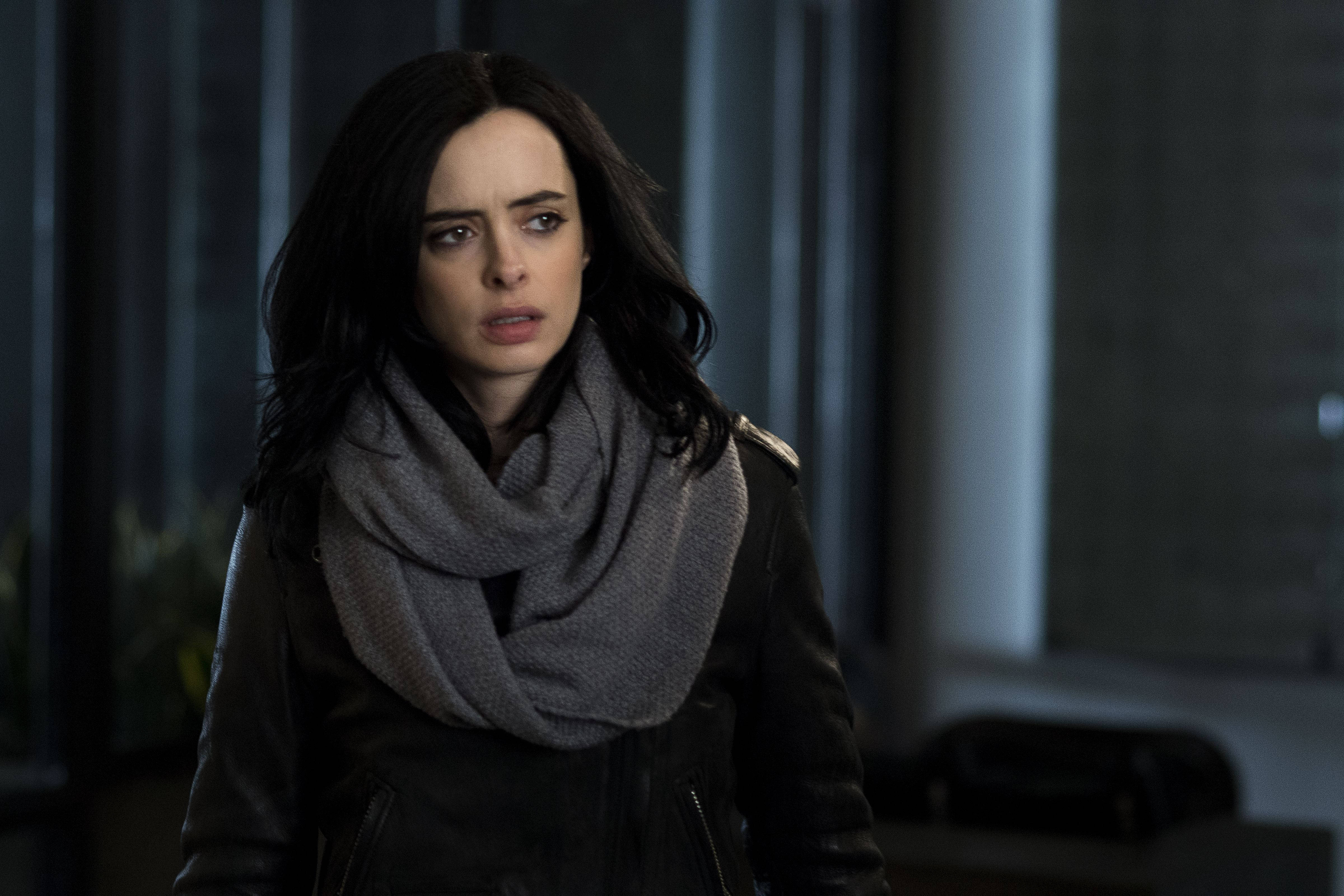 Netflix 桌布 壁紙 — 一位深色頭髮、戴灰色圍巾的女性在光線昏暗的現代室內顯得驚慌。