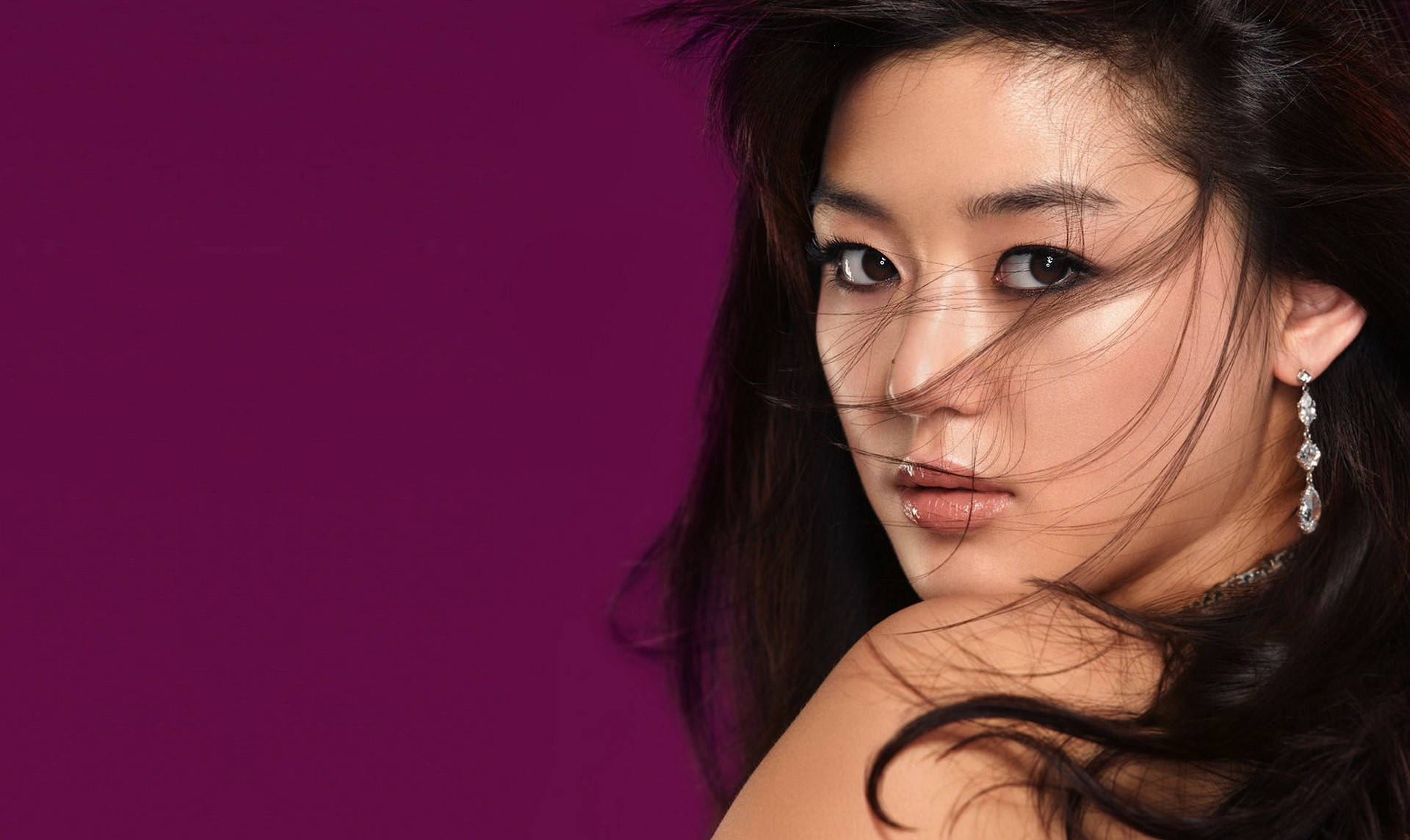 Jun Ji Hyun 桌布 壁紙 — 一位深色頭髮、戴著優雅耳環的女性，在充滿活力的紫色背景下強烈凝視。