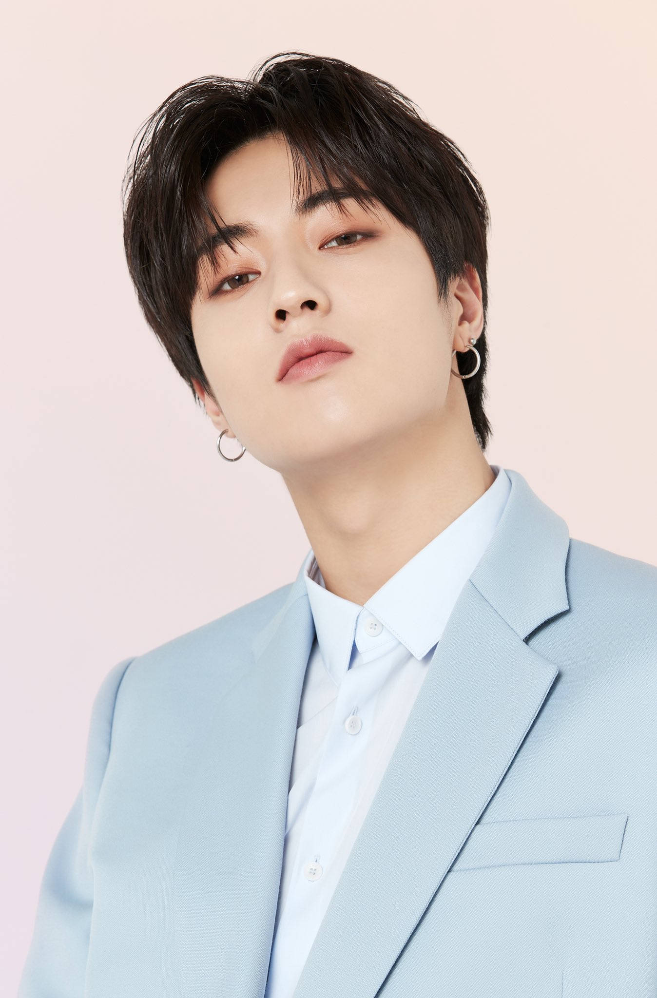 Haruto 桌布 壁紙 — 一位深色頭髮、戴著圈圈耳環的年輕男子，身穿淺藍色西裝，在柔和的粉紅色背景前向上凝視。