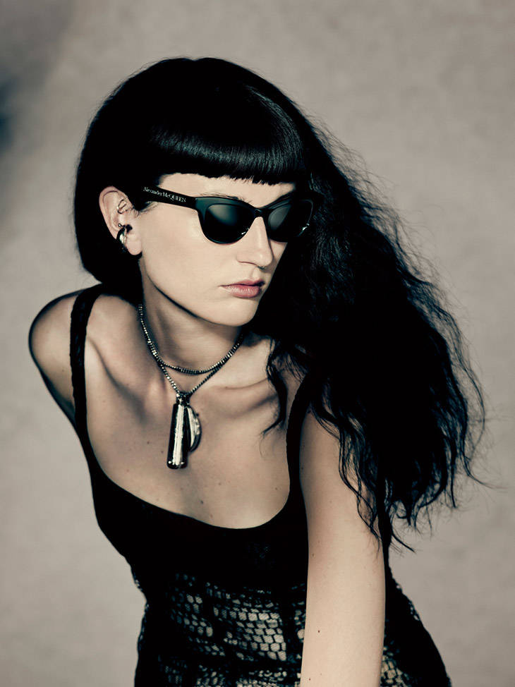 Sunglasses 桌布 壁紙 — 一位深色頭髮、戴著太陽眼鏡的女性，身穿黑色蕾絲上衣，在柔和的灰色背景前擺姿勢。