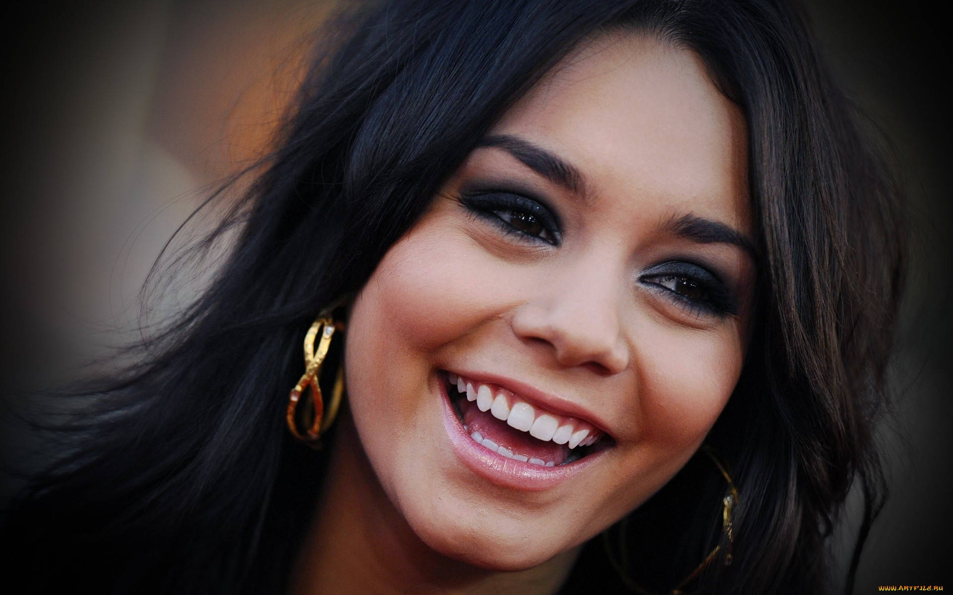 Vanessa Hudgens 桌布 壁紙 — 一位深色頭髮、戴著金色圓環耳環的女性，露出潔白牙齒燦爛微笑的特寫肖像。