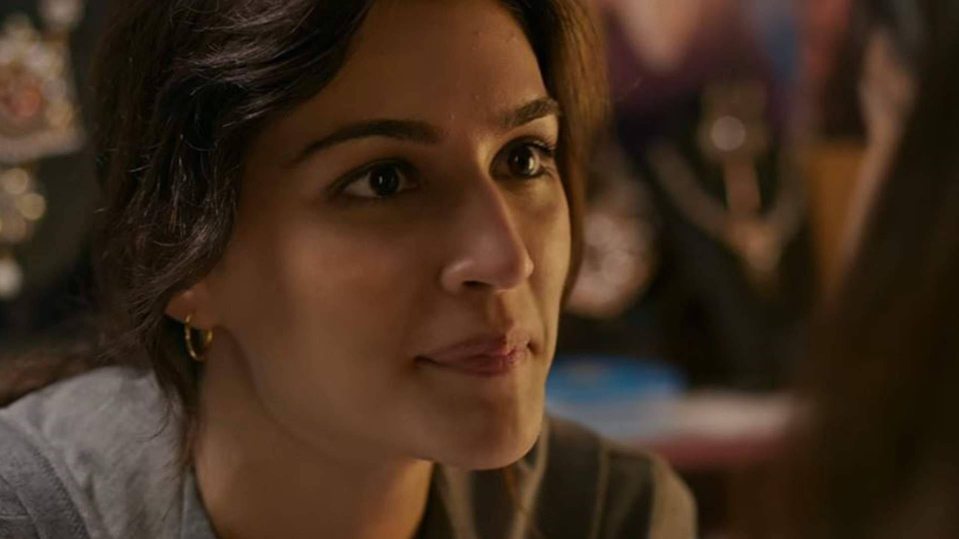 Kriti 桌布 壁紙 — 一位深色頭髮、戴著金色圓環耳環的女性，在溫暖光線的室內環境中若有所思地望向一旁。
