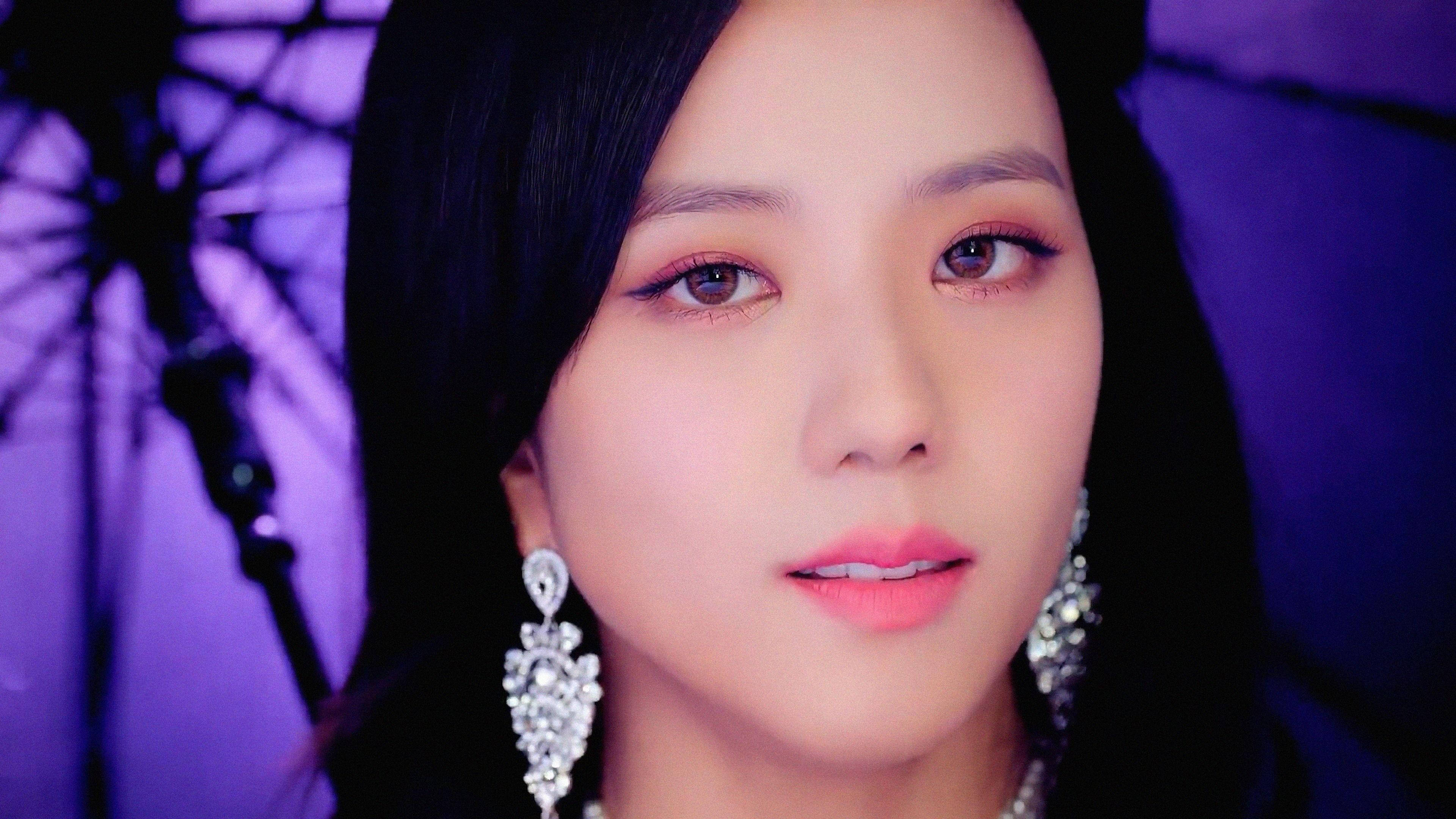 Jisoo Cute 桌布 壁紙 — 一位深色頭髮、戴著閃爍吊燈耳環的女性在紫色燈光背景下的特寫肖像。