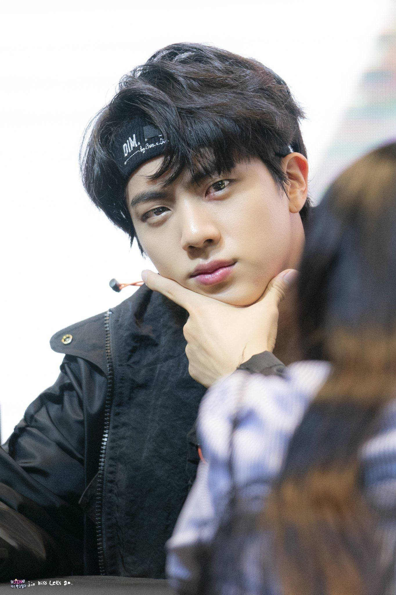 kim seok jin 桌布 壁紙 — 一位深色頭髮、戴黑色帽子的年輕男子，用手托著下巴，若有所思地看著鏡頭外的人。