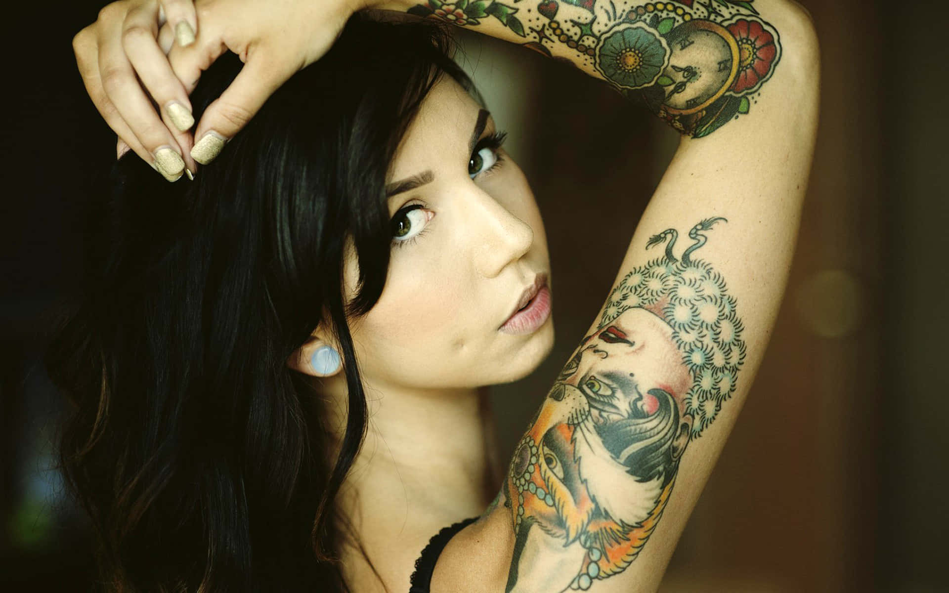 Tattoo Girl 桌布 壁紙 — 一位深色頭髮、手臂上有複雜彩色刺青的女性，帶著沉思的表情向上凝視。
