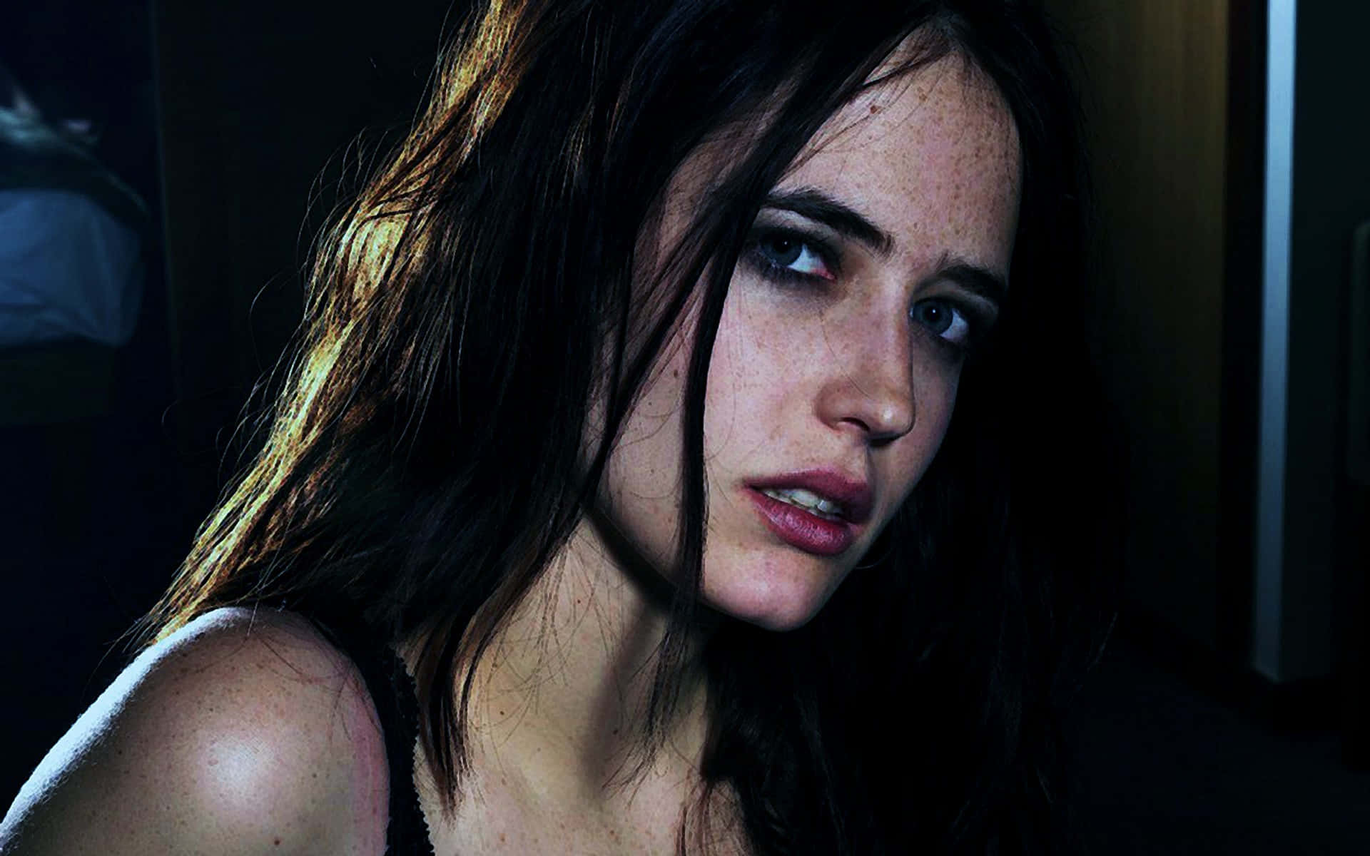 eva green 桌布 壁紙 — 一位深色頭髮、有雀斑的女性在戲劇性的低光下凝視著相機。